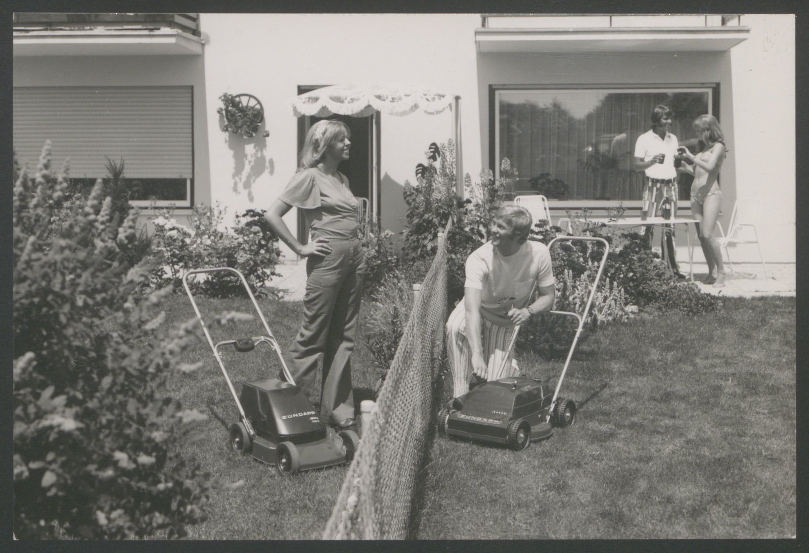 Fotografie: Nachbarn beim Rasenmähen mit Zündapp-Rasenmähern (Stiftung Deutsches Technikmuseum Berlin CC0)