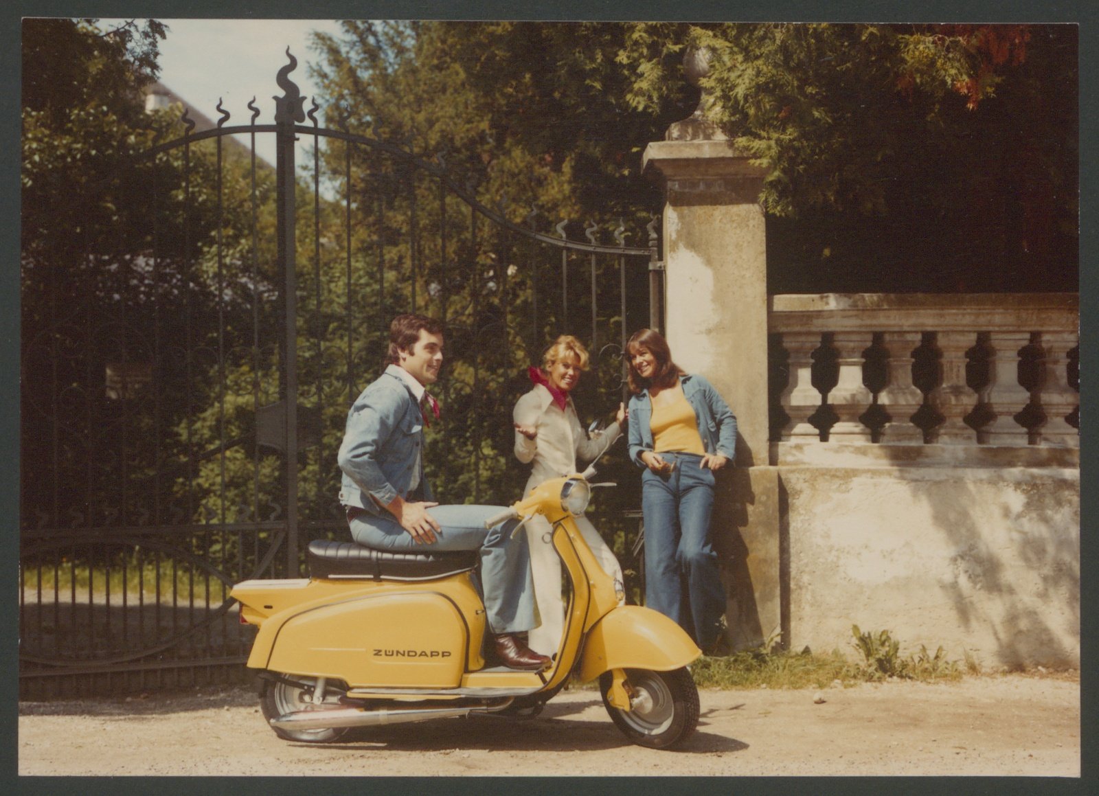 Fotografie: Mann sitzend auf Motorroller, zwei Frauen im Hintergrund (Stiftung Deutsches Technikmuseum Berlin CC0)