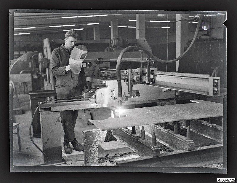Arbeiter an Schneidmaschine im Rohlager (www.industriesalon.de CC BY-NC-SA)