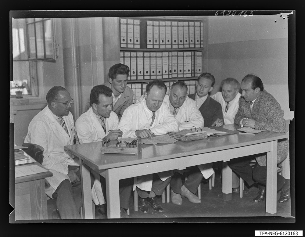 Findbucheintrag: Arbeitsgemeinschaft/Brigade Kirschke 1. Mai, 8 Männer an einem Schreibtisch; Foto, 20. April 1961 (www.industriesalon.de CC BY-NC-SA)