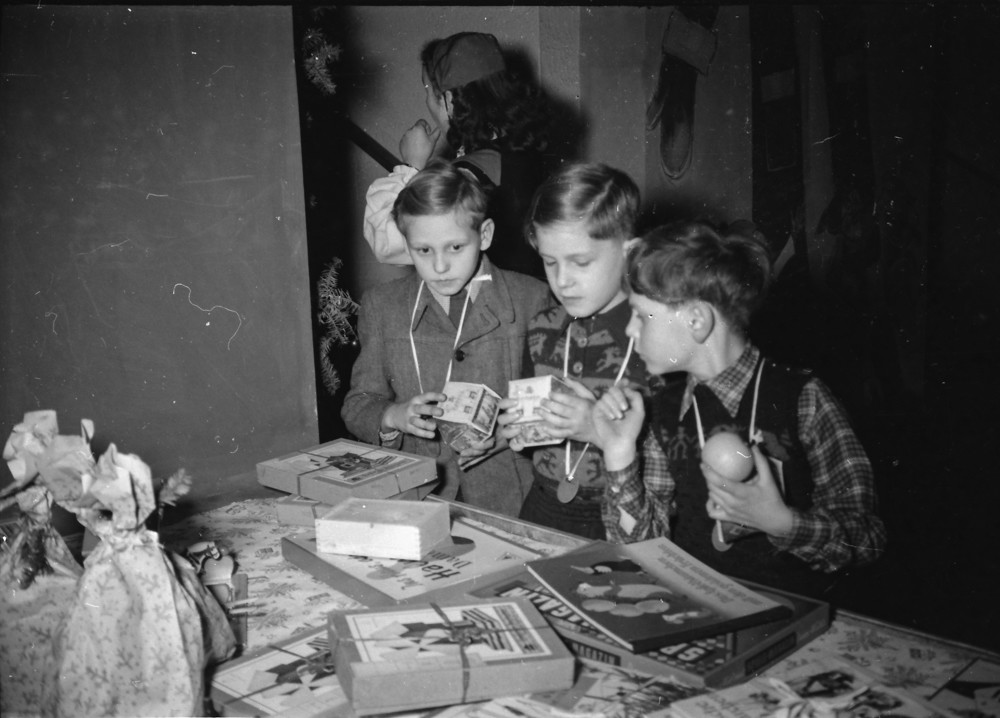 Kinderweihnachtsfest – 3 Jungen vor Geschenktisch; Foto, Dezember 1954 (www.industriesalon.de CC BY-NC-SA)