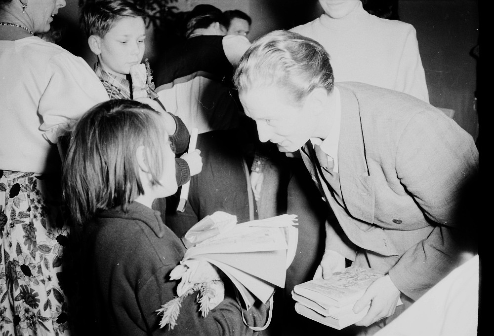 Kinderweihnachtsfest –kleines Mädchen bekommt ein Buchgeschenk überreicht, Foto 1954 (www.industriesalon.de CC BY-NC-SA)