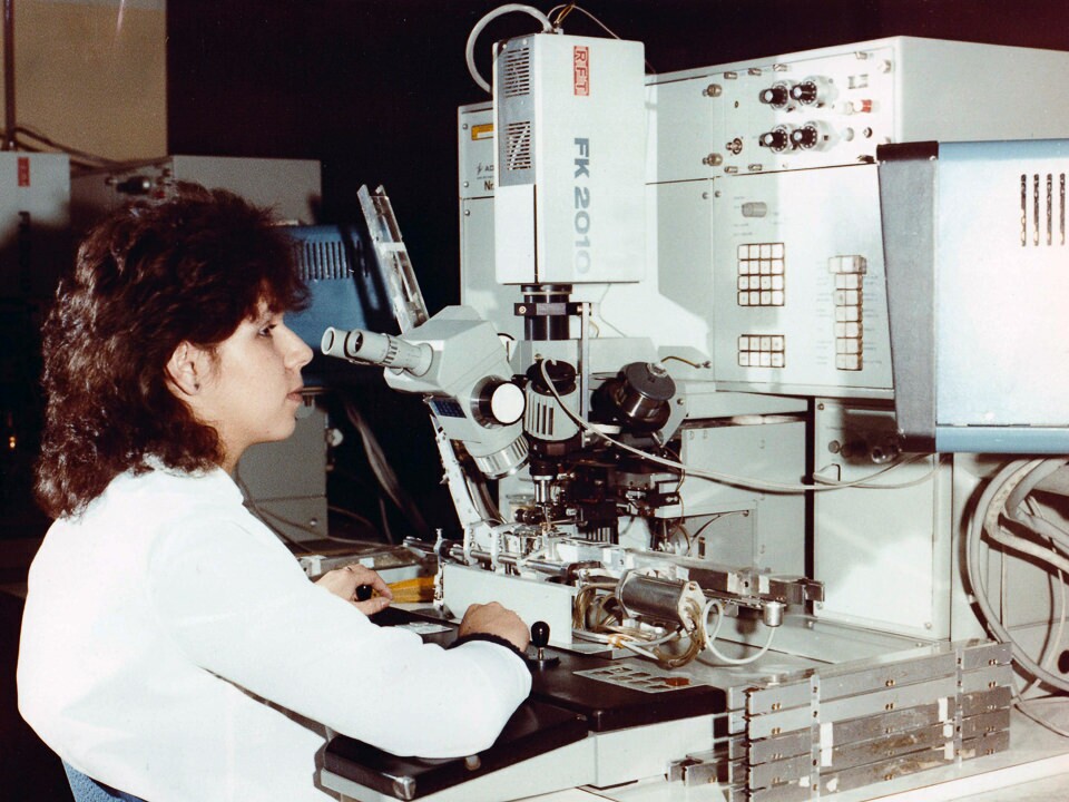 Facharbeiterin für Elektronische Bauelemente bei der Arbeit am Mikroskop, Farbfoto © Kurt Schwarz, 1980er Jahre (Kurt Schwarz CC BY-NC-SA)