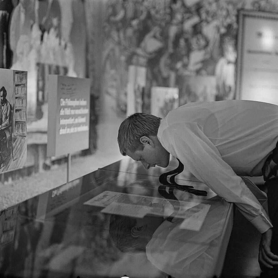 Mann in Ausstellung über eine Vitrine gebeugt, 1960er Jahre SW-Foto © Kurt Schwarz. (Kurt Schwarz CC BY-NC-SA)