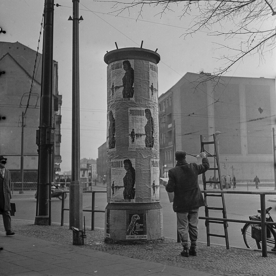 Plakatankleber eine Litfass-Säule beklebend, 1964. SW-Foto © Kurt Schwarz. (Kurt Schwarz CC BY-NC-SA)