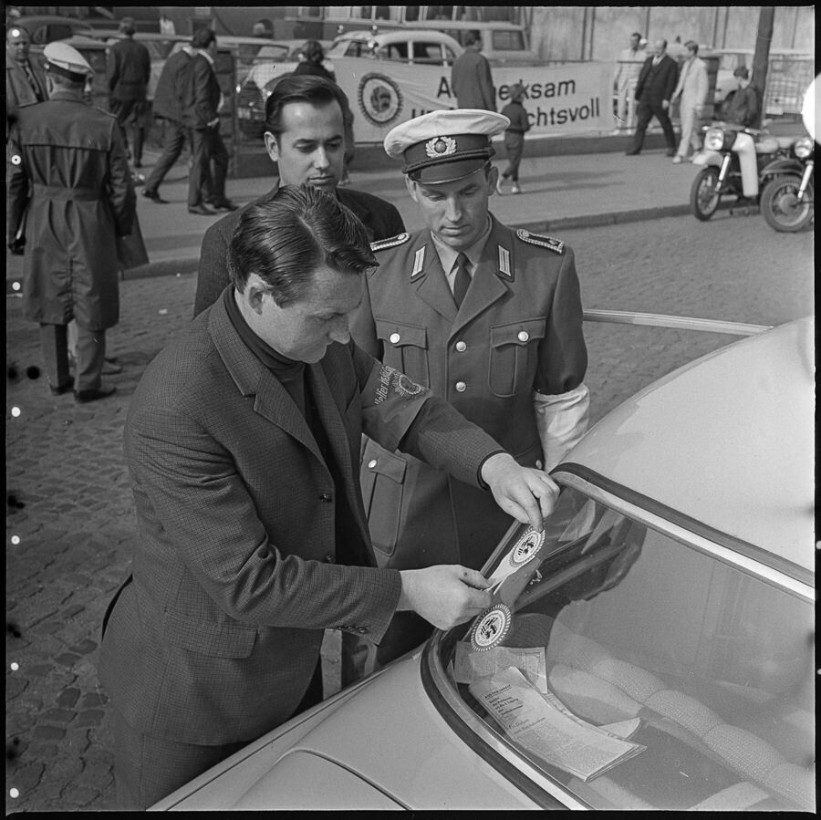 Autofahrer befestigt Emblem an Windschutzscheibe, 1968. SW-Foto © Kurt Schwarz. (Kurt Schwarz CC BY-NC-SA)