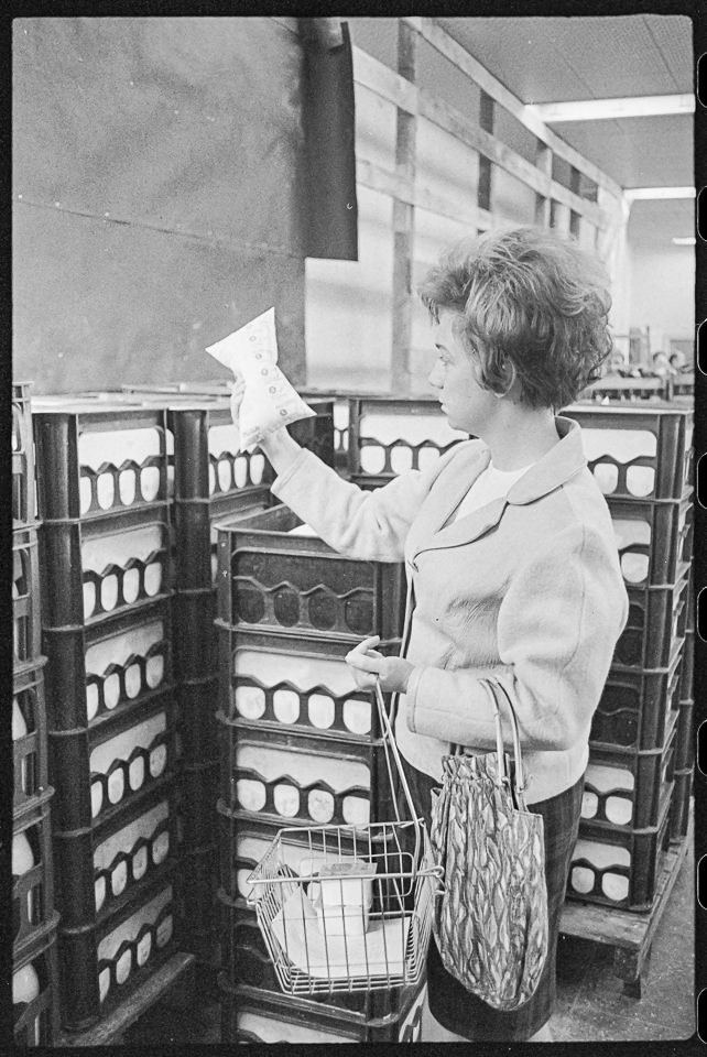 Kundin in Kaufhalle betrachtet in Schlauchtüte abgepackte Milch, , März 1969. SW-Foto © Kurt Schwarz. (Kurt Schwarz CC BY-NC-SA)
