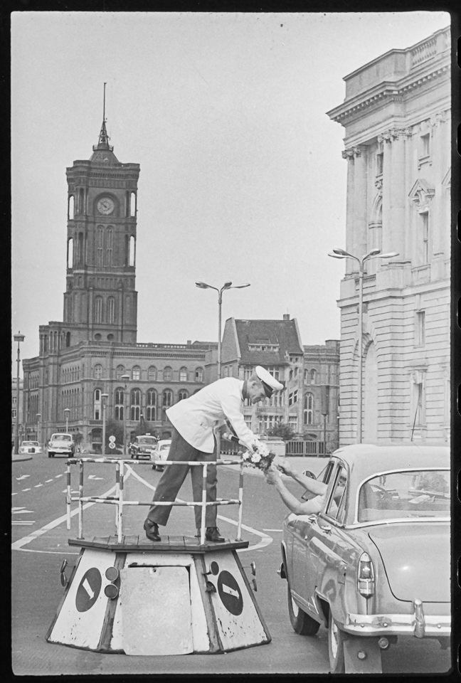 Verkehrspolizist wird aus einem Auto ein Blumenstrauß gereicht, Juli 1965. SW-Foto © Kurt Schwarz. (Kurt Schwarz CC BY-NC-SA)