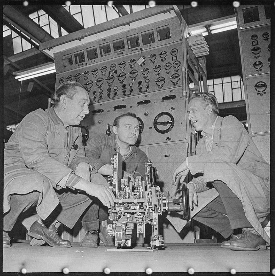 VEB Kühlautomat Berlin, Bild 2: Drei Männer bei einer Arbeitsbesprechung in einer Fabrikhalle. SW-Foto, 1960er Jahre © Kurt Schwarz. (Kurt Schwarz CC BY-NC-SA)
