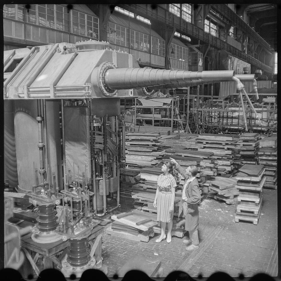 Transformatorenwerk Oberschöneweide (TRO), Bild 1: Blick in die Fabrikhalle, ein Mann zeigt einer Frau einen fast fertigen Leistungstransformator. SW-Foto, (Kurt Schwarz CC BY-NC-SA)