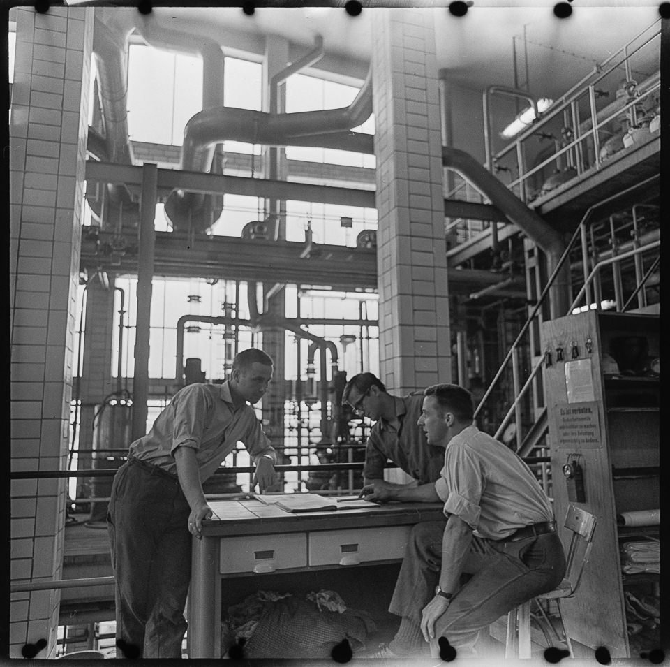 VEB Chemische Fabrik Grünau, Bild 1: Drei Männer bei einer Arbeitsbesprechung in einer Fabrikhalle. SW-Foto, August 1968 © Kurt Schwarz. (Kurt Schwarz CC BY-NC-SA)