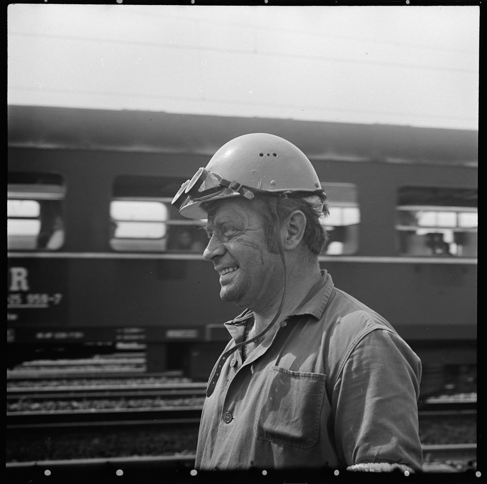 Porträt eines Abeiters mit Helm und Schutzbrille vor einem vorbeifahrendem Personenzug. SW-Foto, wahrscheinlich 1960er Jahre © Kurt Schwarz. (Kurt Schwarz CC BY-NC-SA)