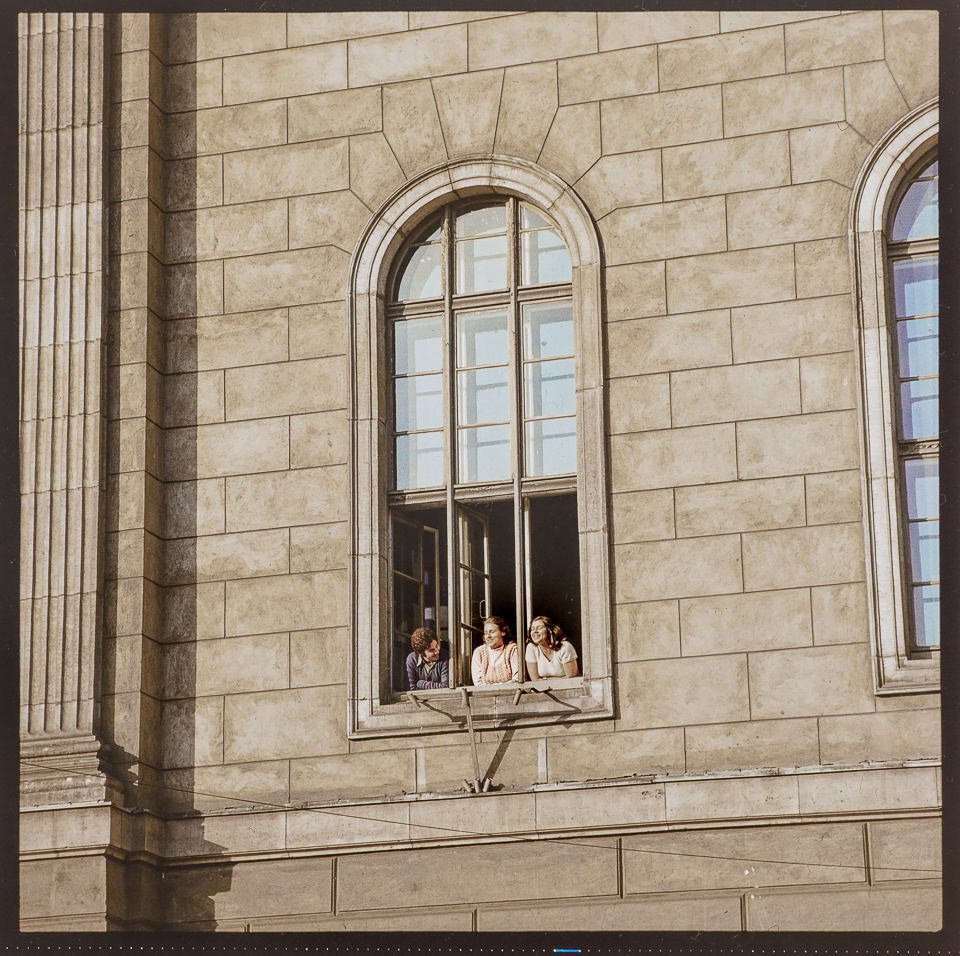 Drei Studenten aus einem Fenster der Humboldt-Universität schauend. Farbfoto, 1974 © Kurt Schwarz. (Kurt Schwarz CC BY-NC-SA)