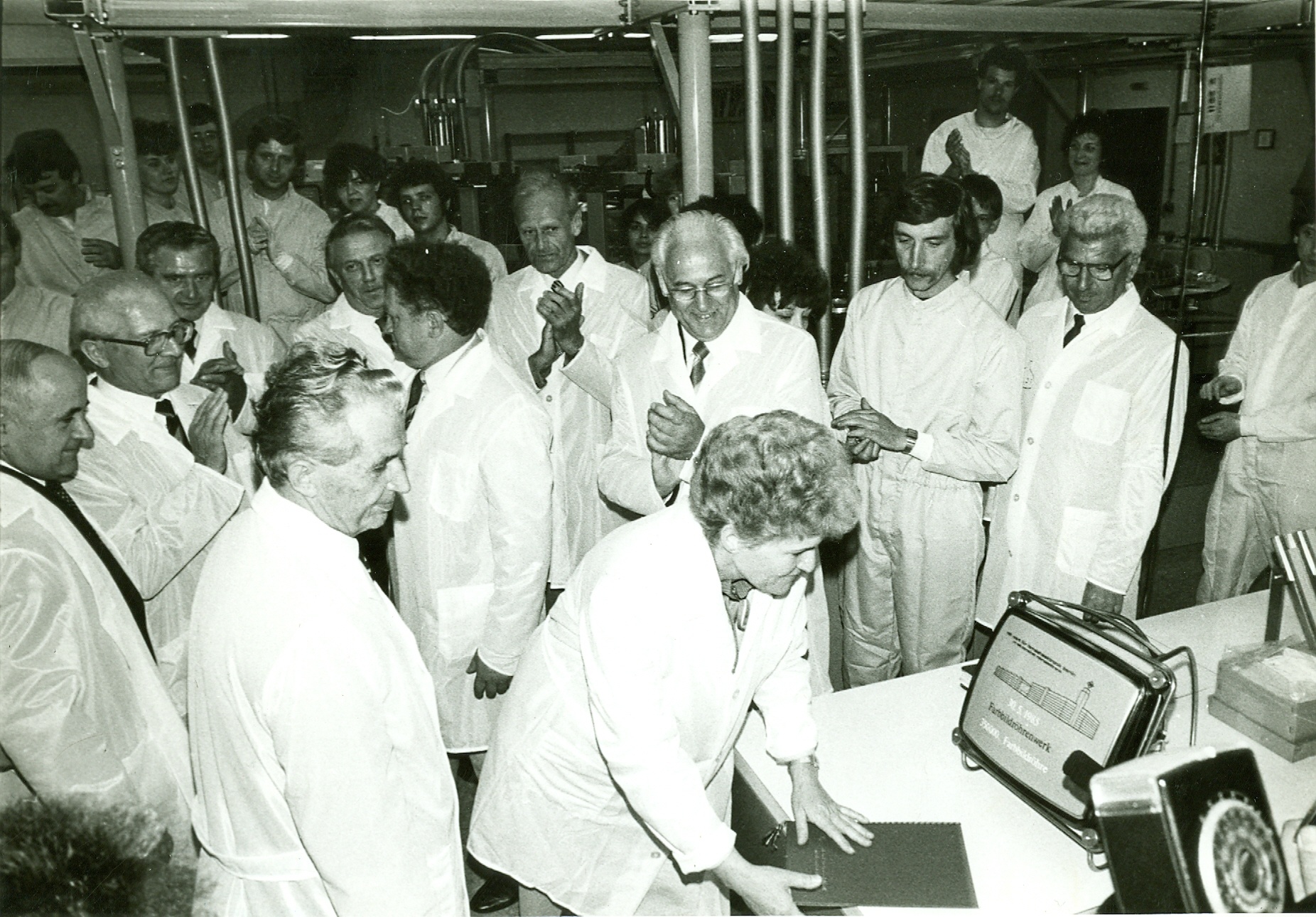 Personen in Reinraumkleidung mit Honecker bei Einschmelze, Farbbildröhre mit Aufschrift "30.5.1985 350000 Farbbildröhre", Haus L (Industriesalon Schöneweide CC BY-NC-SA)