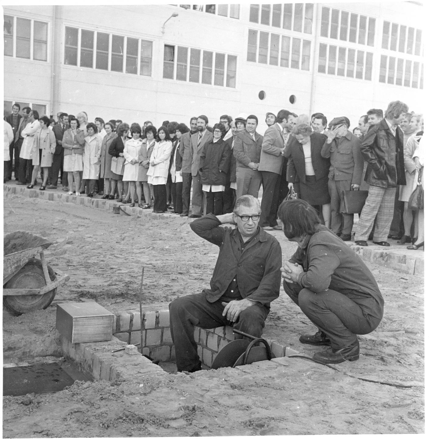 Grundsteinlegung (Kassette links vorne im Bild, zwei Männer an Grube, im Hintergrund Menschenmenge (Industriesalon Schöneweide CC BY-SA)