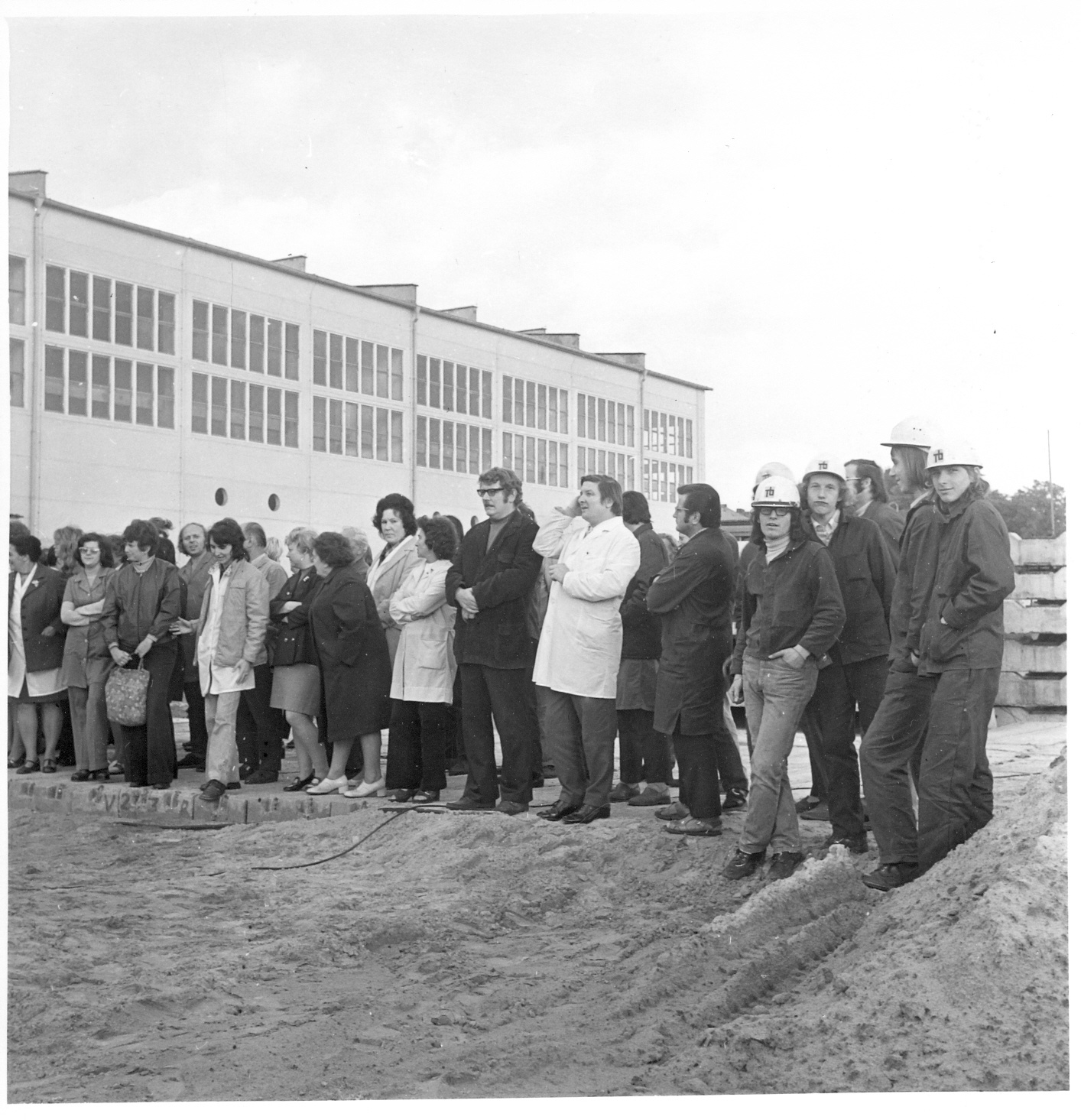 Menschenmenge schaut bei Grundsteinlegung zu, u.a. vorne rechts Gruppe von Arbeitern mit Bauhelmen (Industriesalon Schöneweide CC BY-SA)