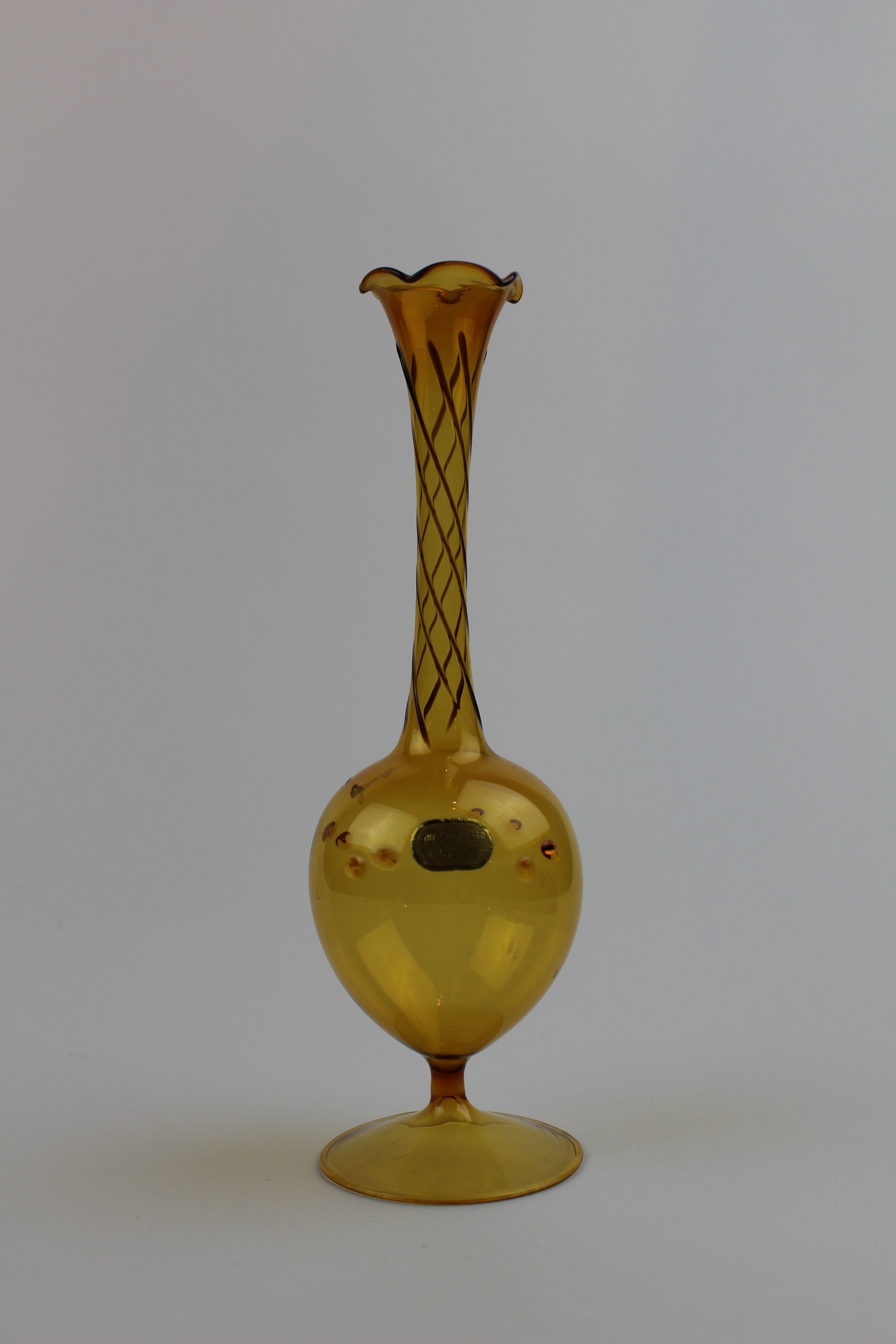 Bernsteinfarbene Vase mit farbigen Verzierungen und Aufkleber (Museum Baruther Glashütte CC BY-NC-SA)