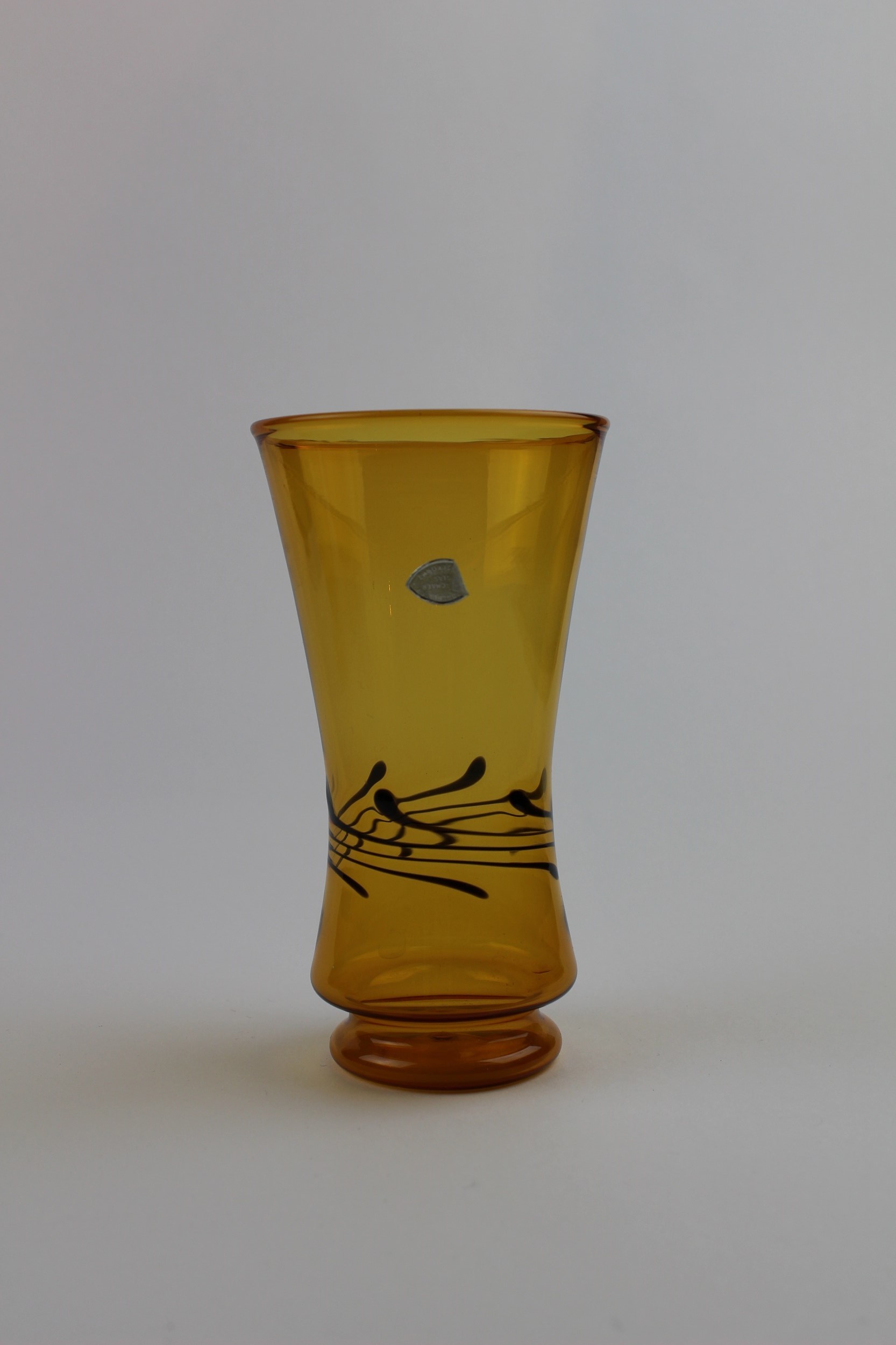 Bernsteinfarbene Vase mit farbigen Verzierungen und Aufkleber (Museum Baruther Glashütte CC BY-NC-SA)