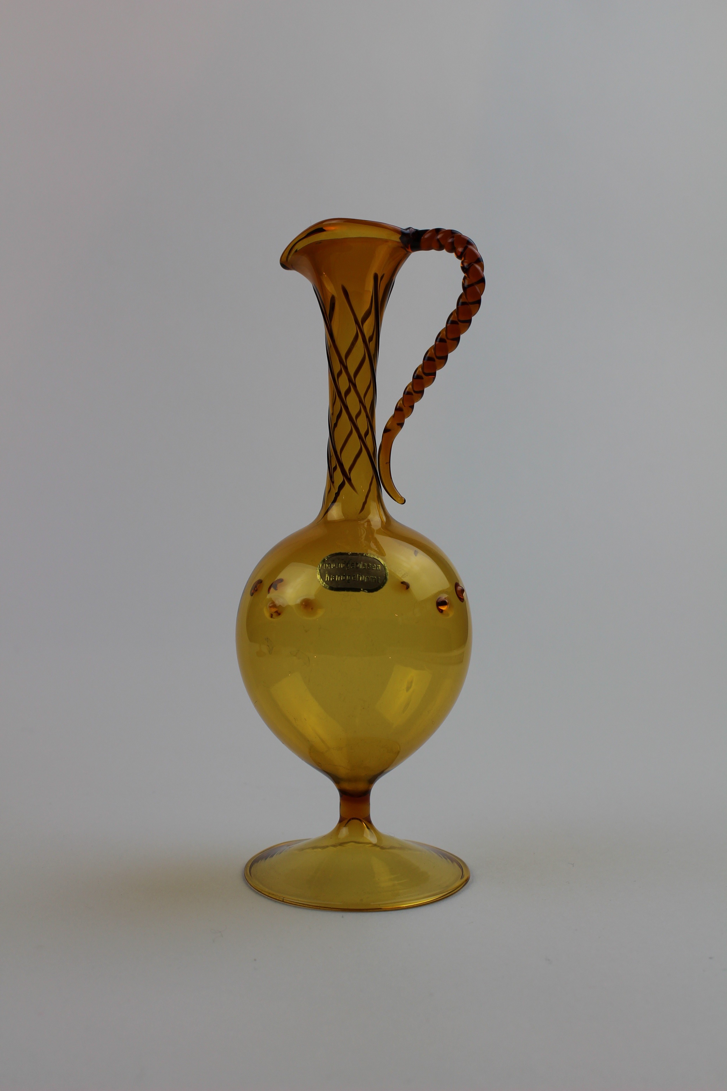 Bernsteinfarbene Vase/Glaskaraffe mit Aufkleber (Museum Baruther Glashütte CC BY-NC-SA)