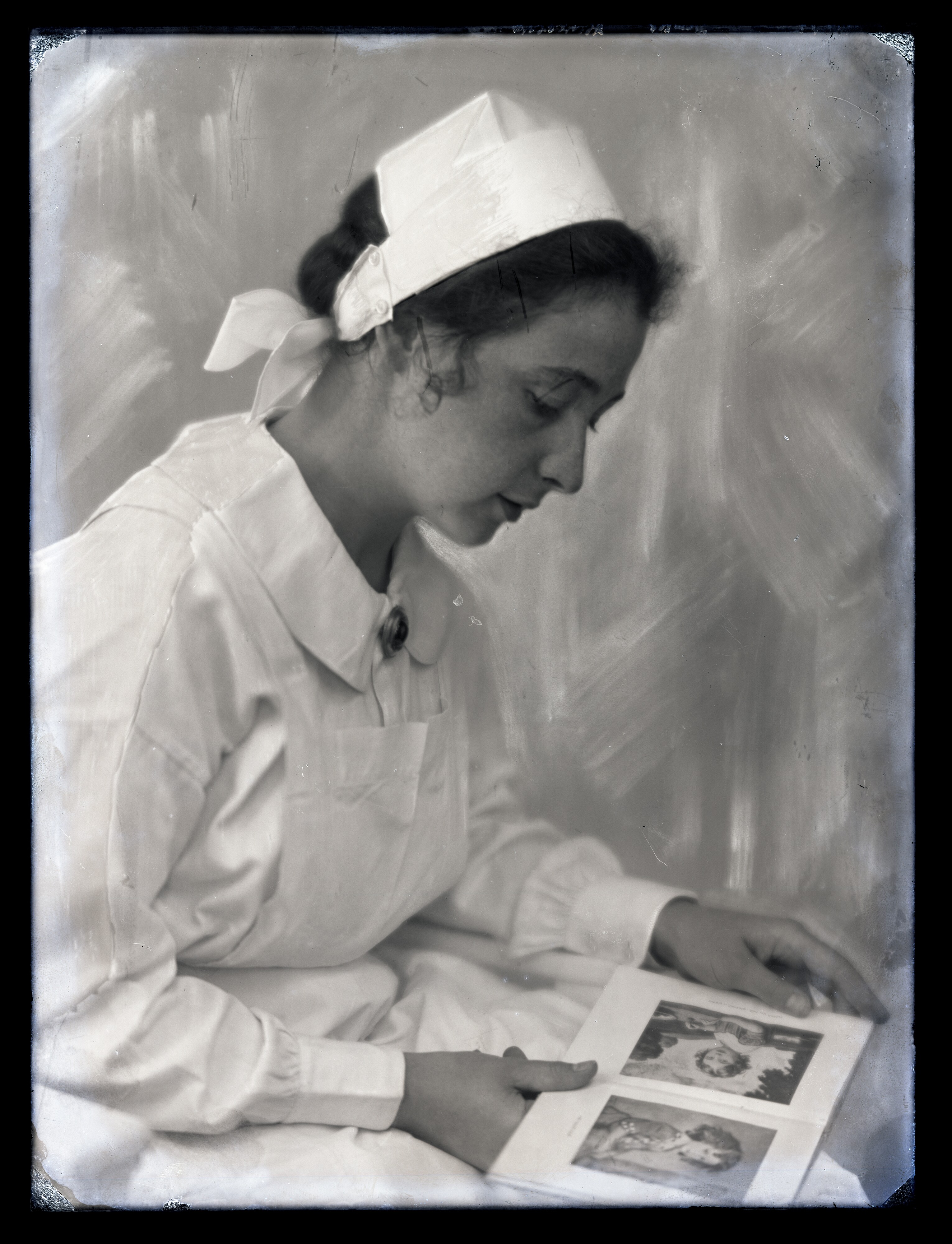 Krankenschwester betrachtet Kinderfotografien (Stadtmuseum Cottbus CC BY-NC-SA)