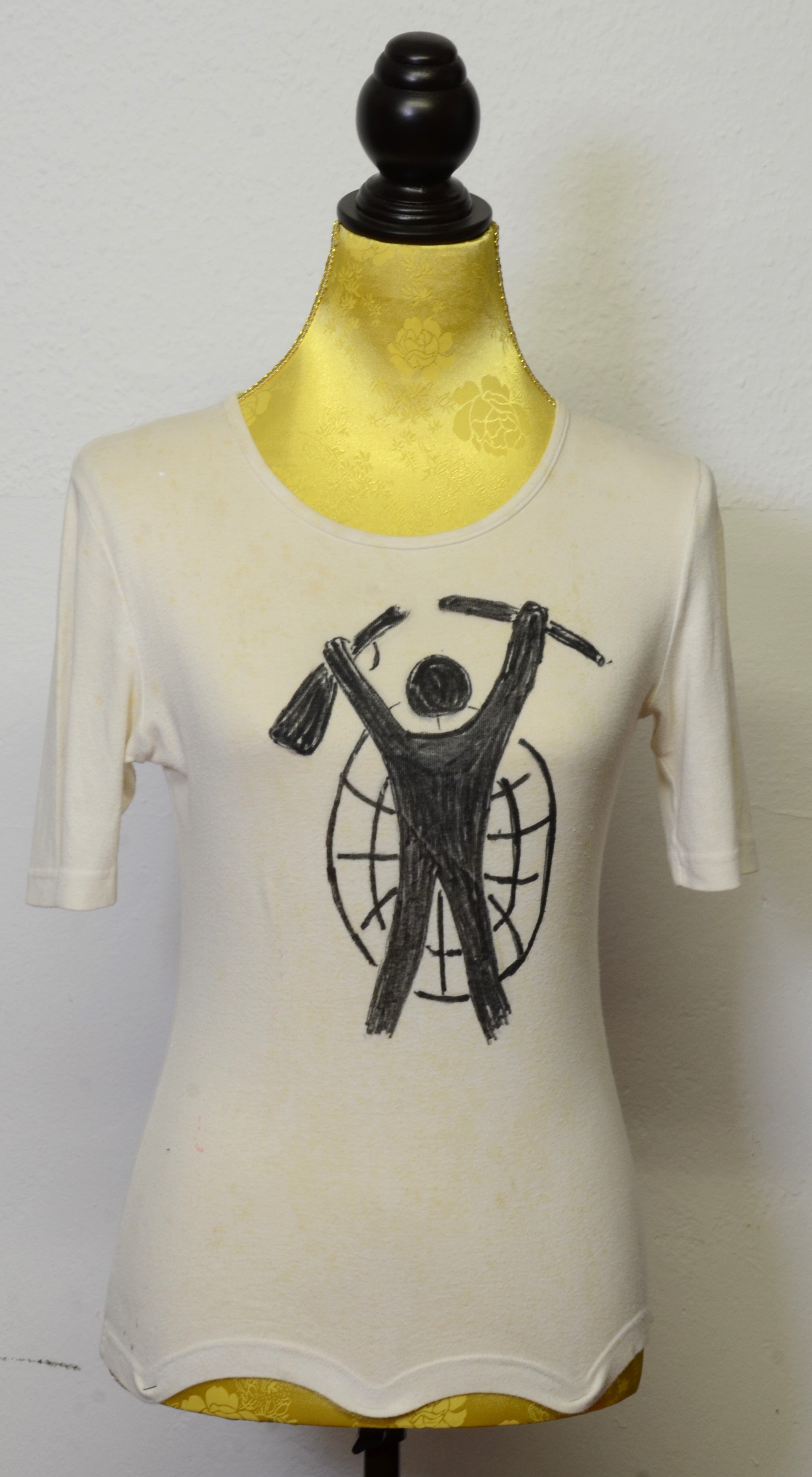 T-Shirt von Gisela Freimark mit dem Motiv eines Mannes mit zerbrochenem Gewehr vor einer Weltkugel (DDR Geschichtsmuseum im Dokumentationszentrum Perleberg CC BY-SA)