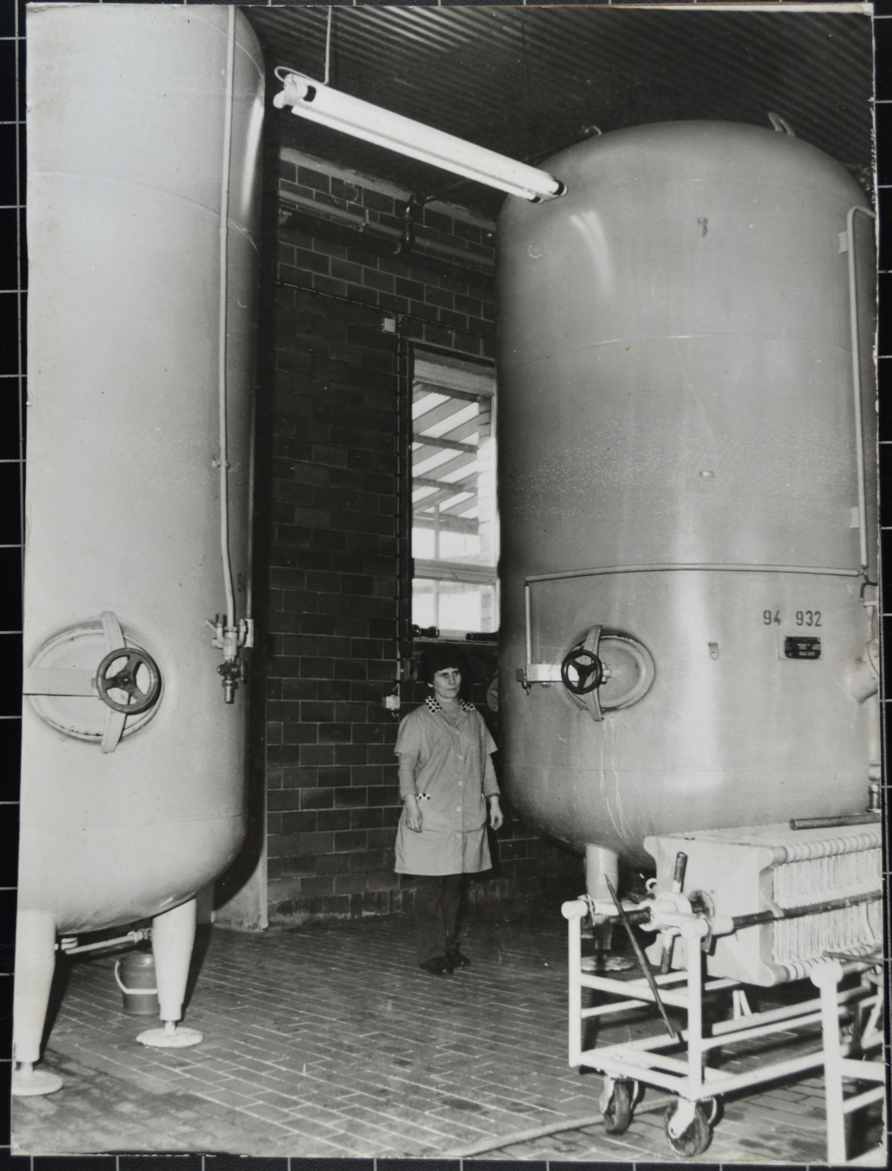 Getränkeproduktion: Arbeiterin zwischen zwei Tanks (DDR Geschichtsmuseum im Dokumentationszentrum Perleberg CC BY-SA)