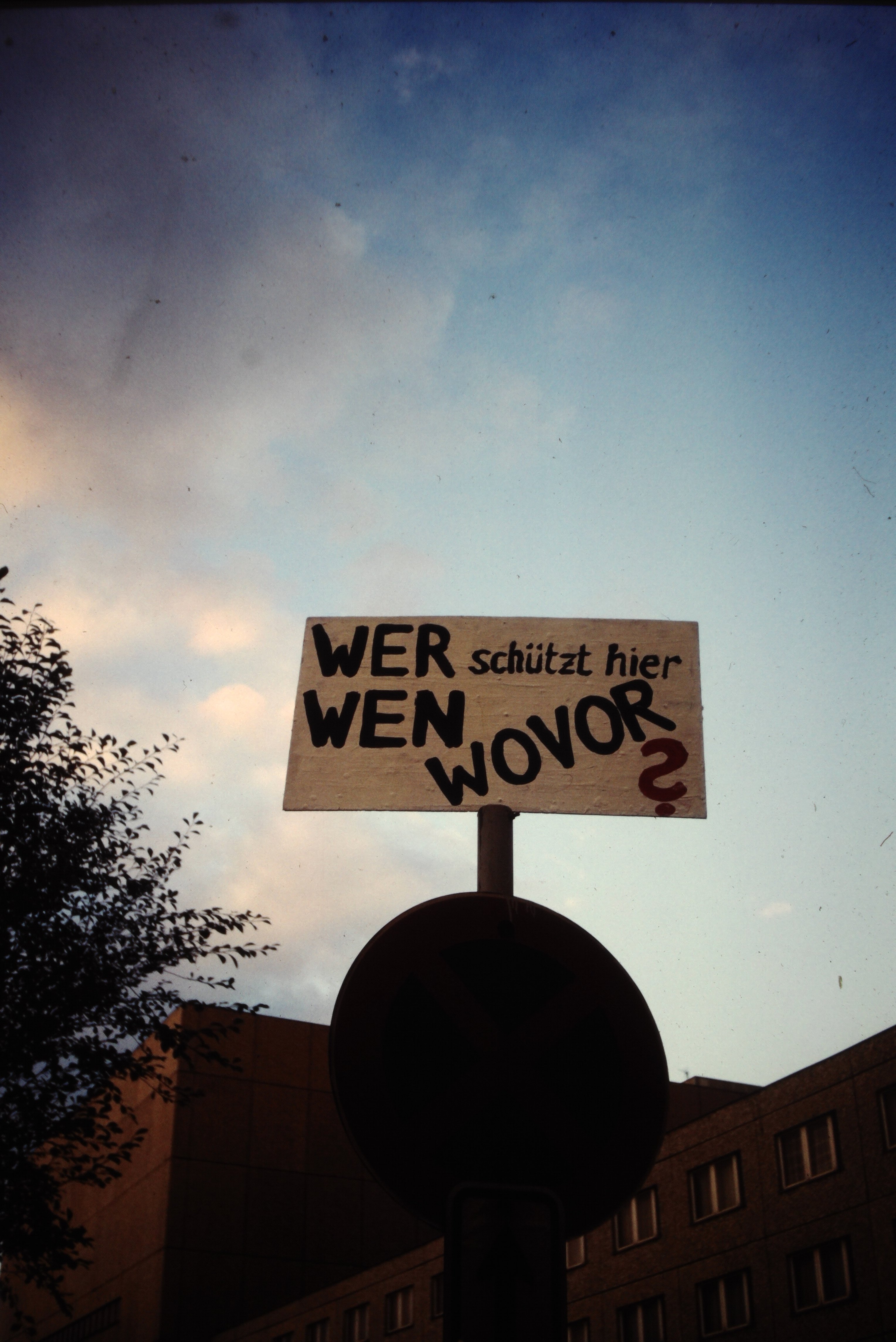 Zentrale der Staatsicherheit in Berlin: Plakat mit der Aufschrift "Wer schützt hier wen wovor?" (DDR Geschichtsmuseum im Dokumentationszentrum Perleberg CC BY-SA)