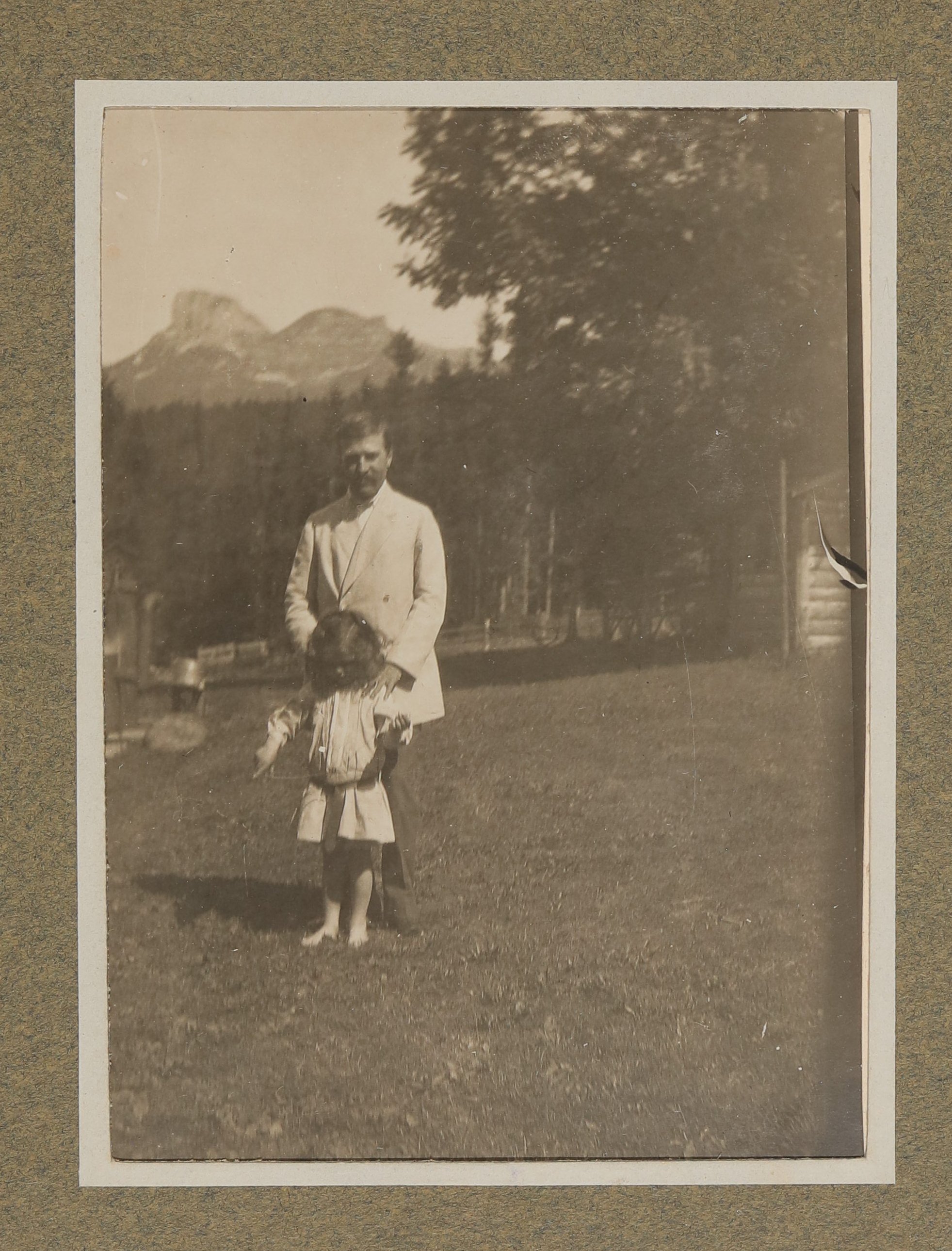 Hugo von Hofmannsthal mit einem Kind (Raimund oder Christiane?) im Garten vor Bergen stehend (Vera Graaf CC BY-NC-SA)