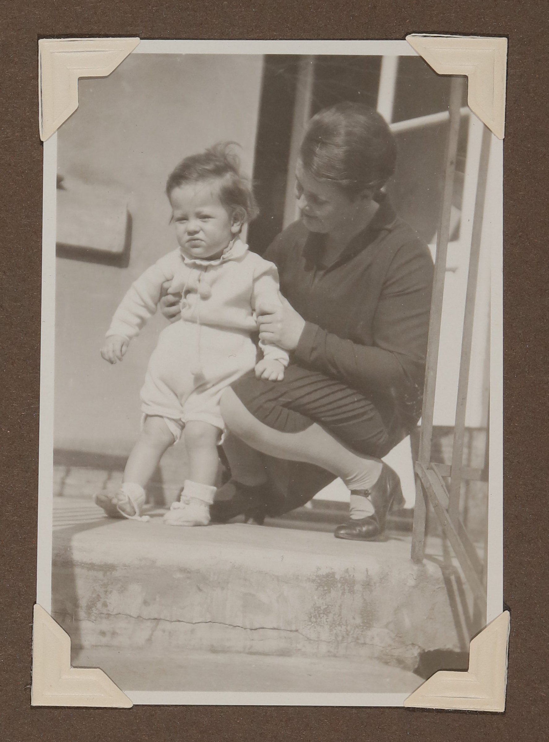 Eine dunkelhaarige Frau kniet neben Christiane Zimmers Sohn Christoph auf dem Balkon (Vera Graaf CC BY-NC-SA)