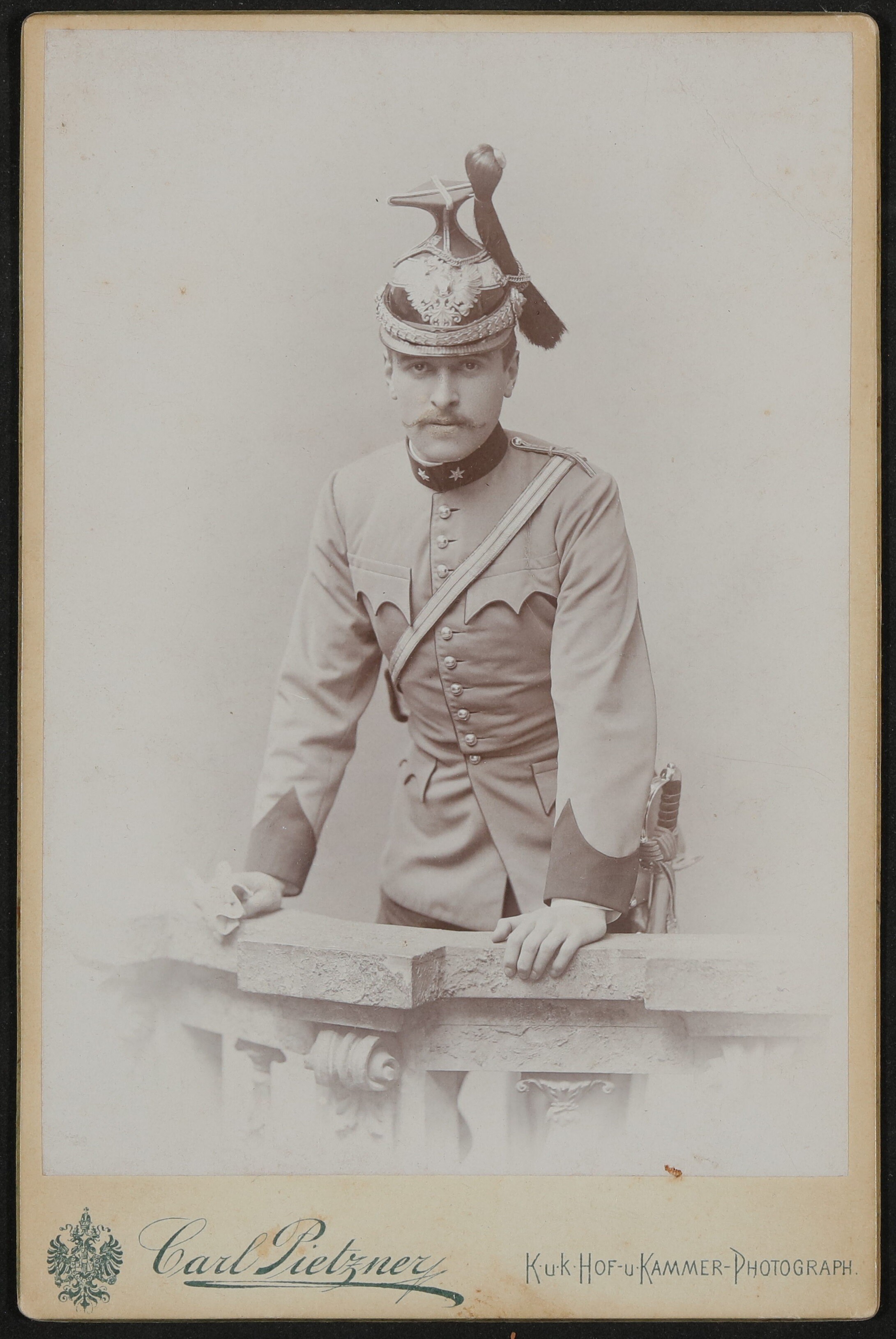 Hofmannsthal als junger Mann mit Zwirbelbart in Uniform mit Helm, lehnt auf eine Balustrade (Freies Deutsches Hochstift / Frankfurter Goethe-Museum CC BY-NC-SA)