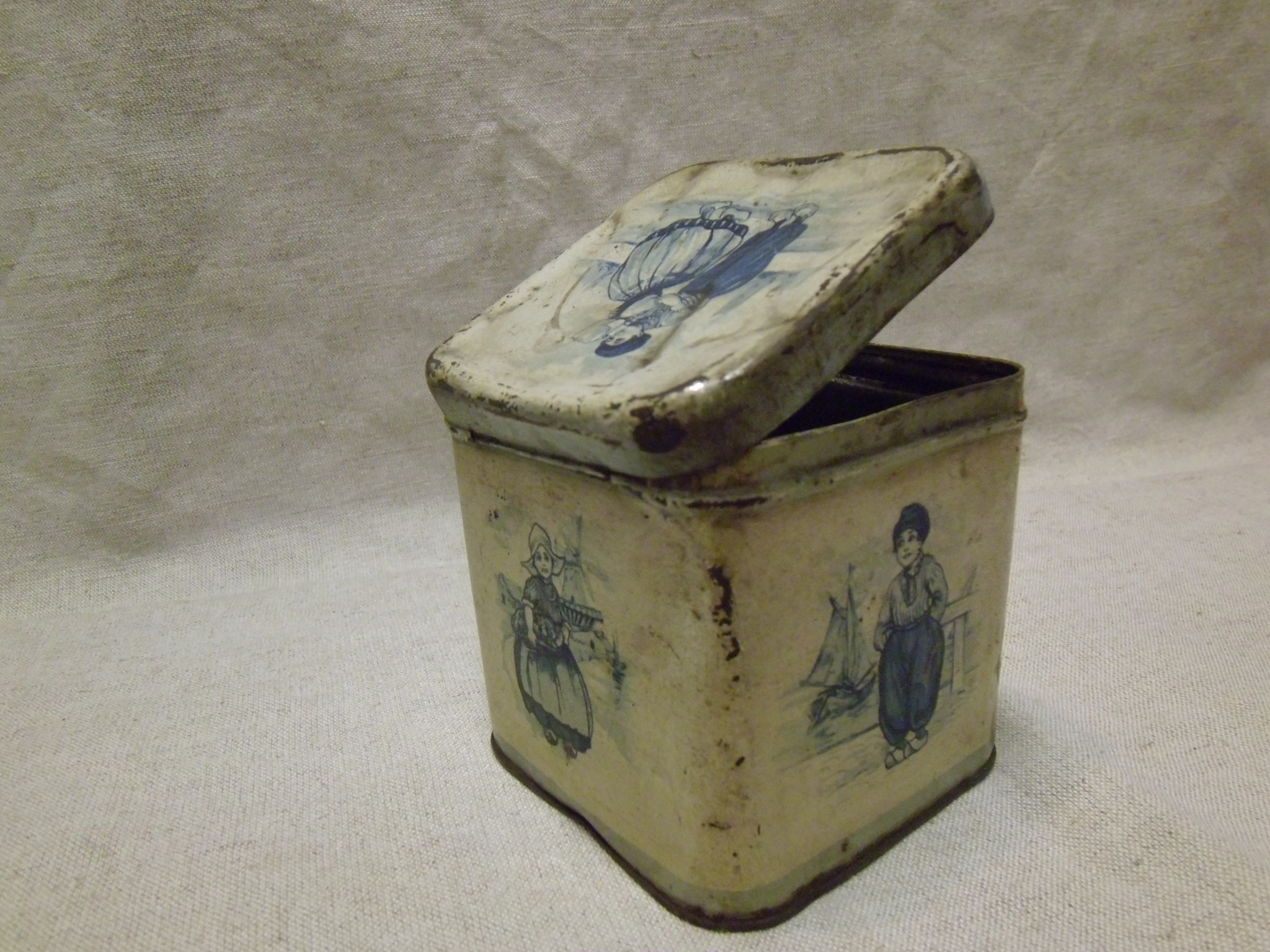 Élelmiszeres doboz, fém, kocka alakú, fehér alapon, kék holland figurák (Tomory Lajos Pedagógiai és Helytörténeti Gyűjtemény CC BY-NC-SA)