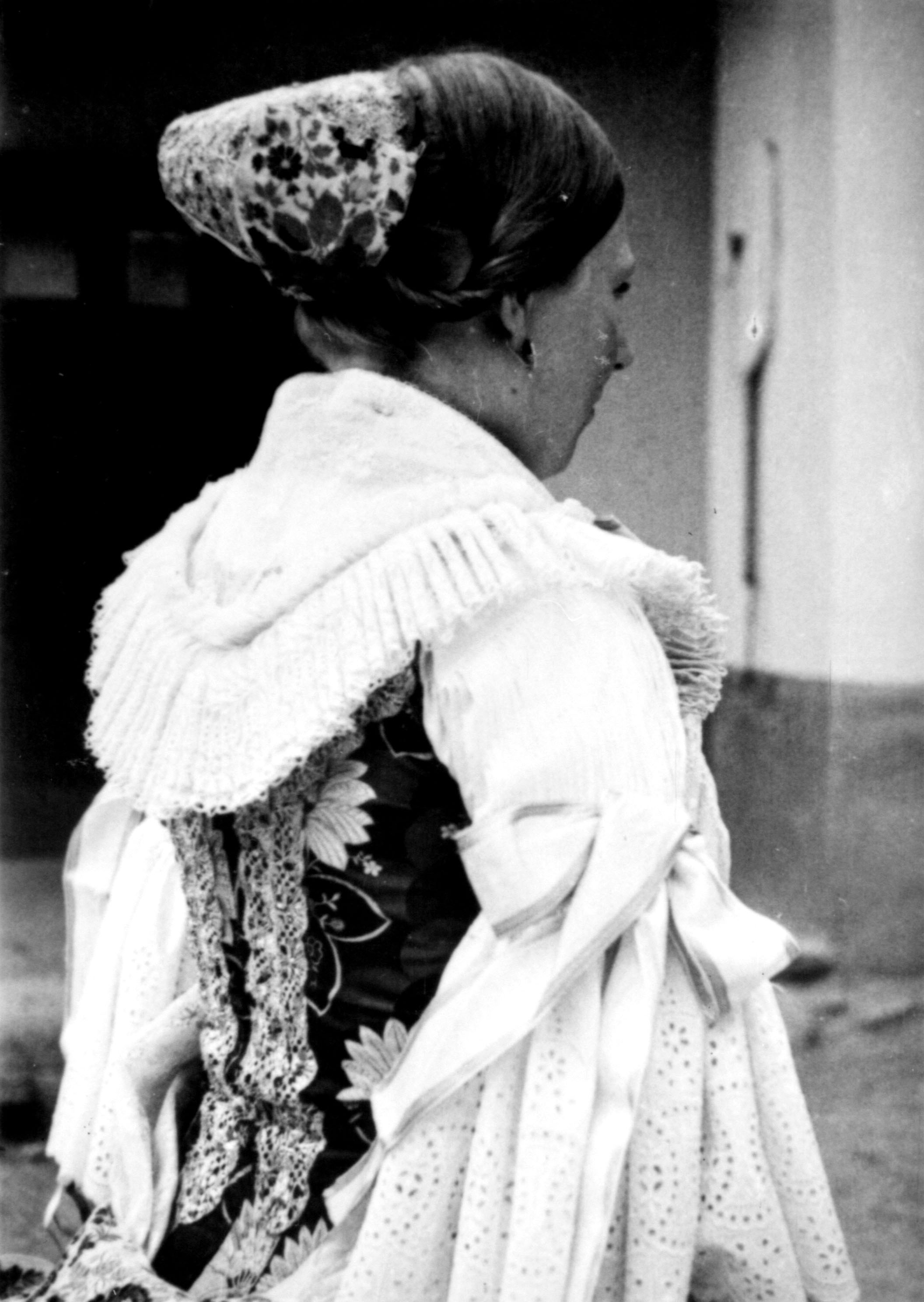 Lány ünnepi viseletben féketővel (MTA BTK Néprajztudományi Intézet CC BY-NC-SA)