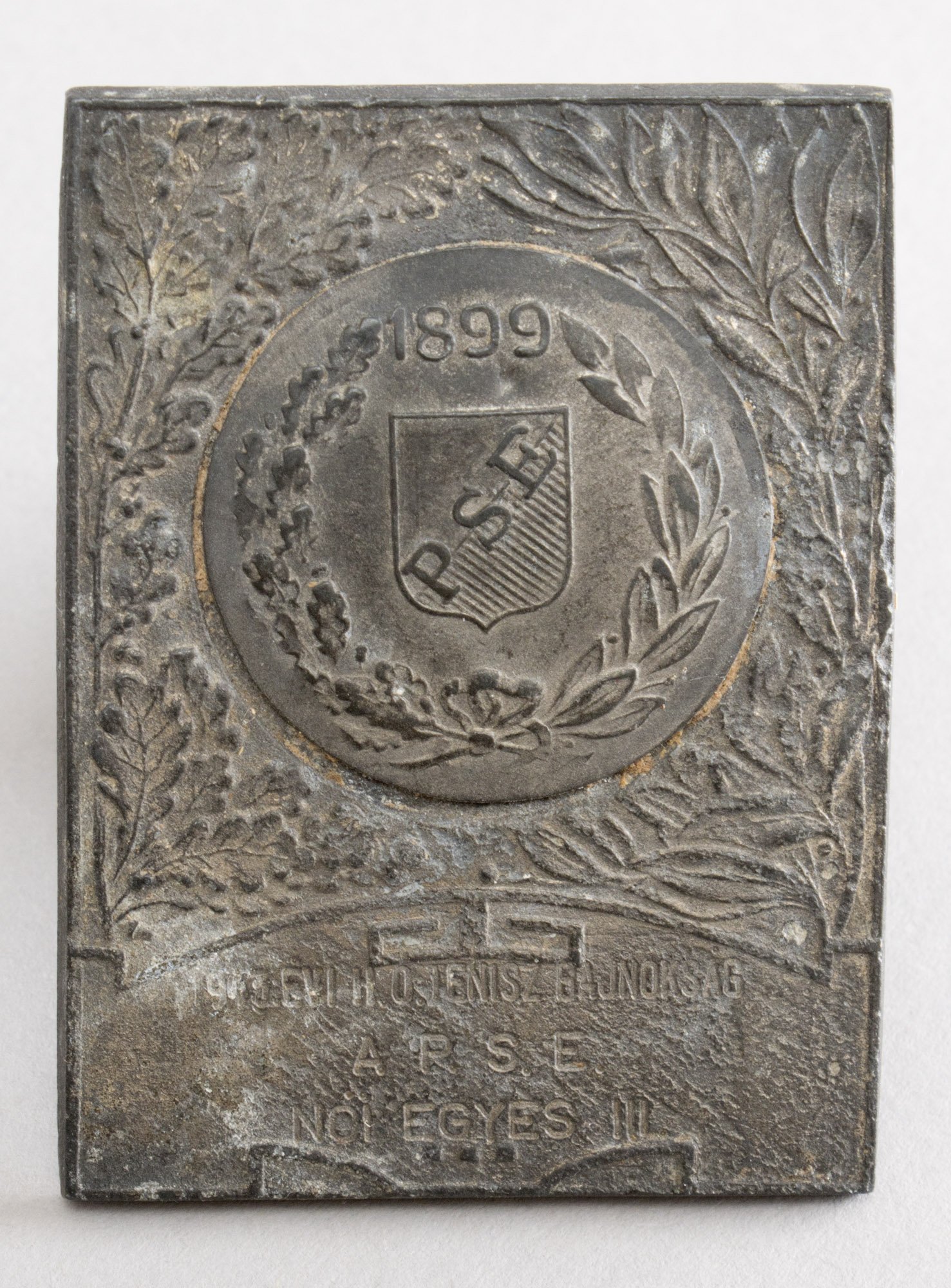 Emlékplakett (bronz) „PSE 1899 1943. ÉVI II. O. TENISZBAJNOKSÁG A P.S.E. NŐI EGYES III.” (Postamúzeum CC BY-NC-SA)
