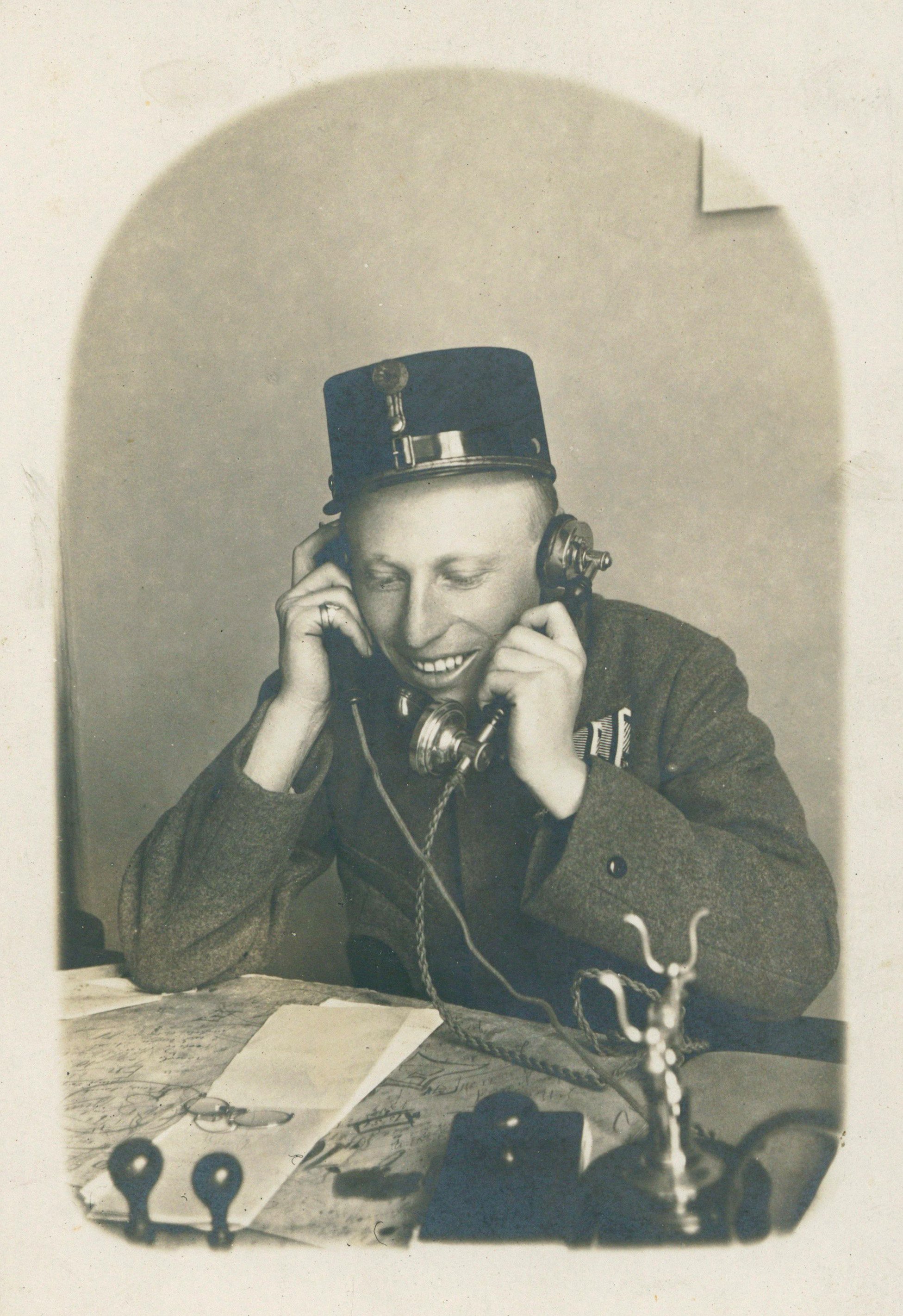 Egyenruhás postás mindkét kezében telefonnal (Postamúzeum CC BY-NC-SA)