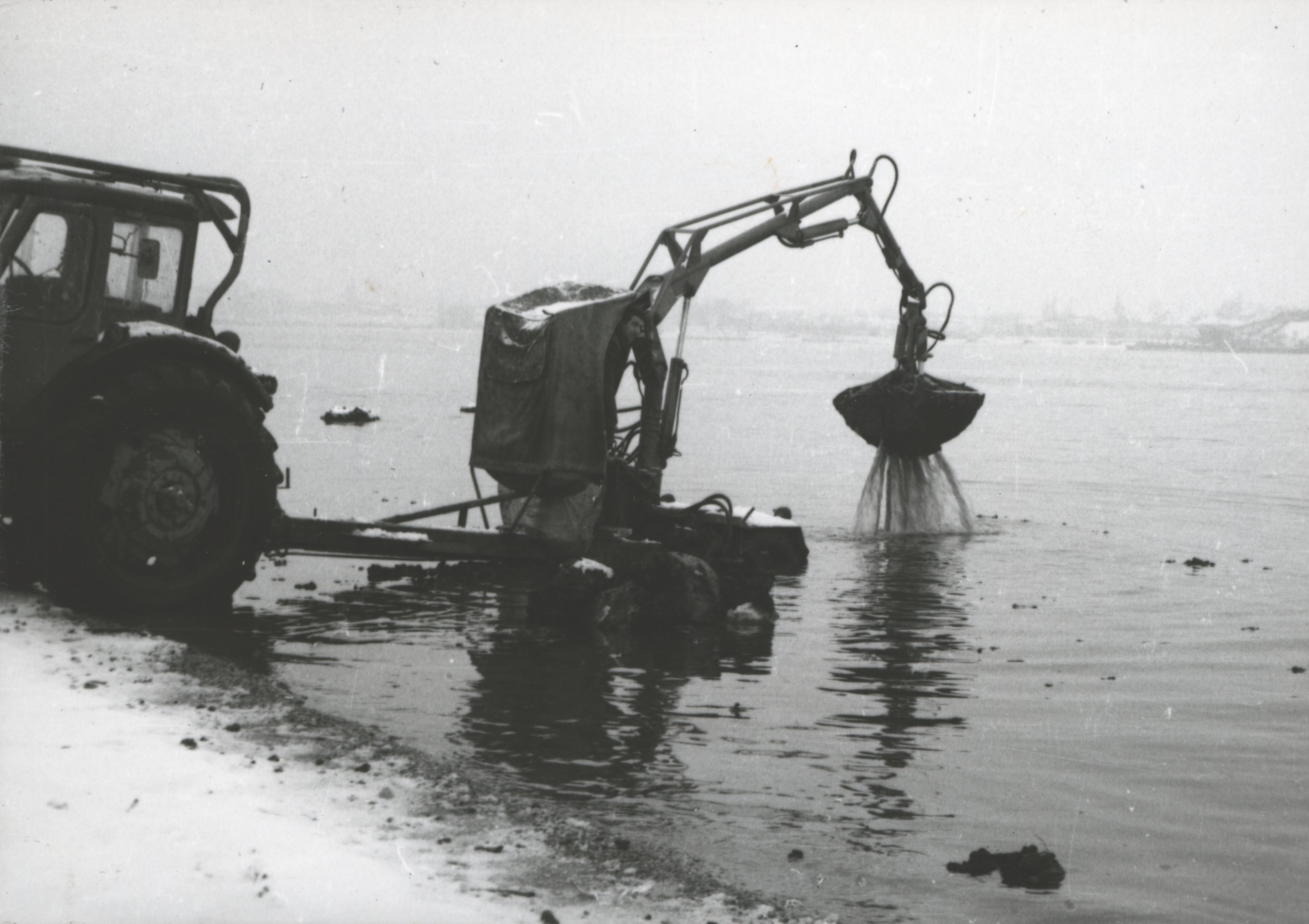 Mezőgazdasági rakodógép partközeli sekély vízből pakura darabot emel ki (Magyar Környezetvédelmi és Vízügyi Múzeum - Duna Múzeum CC BY-NC-SA)