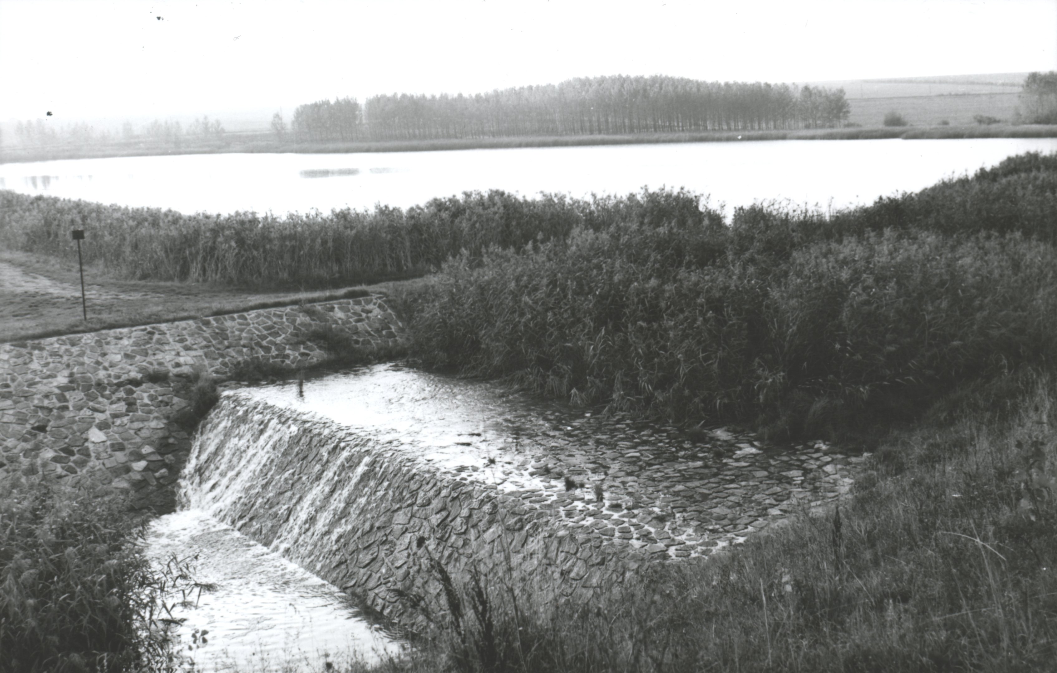 A Gyöngyösoroszi alsó tározó völgyzáró gátja, előtérben az árapasztó csatorna bukójával (Magyar Környezetvédelmi és Vízügyi Múzeum - Duna Múzeum CC BY-NC-SA)