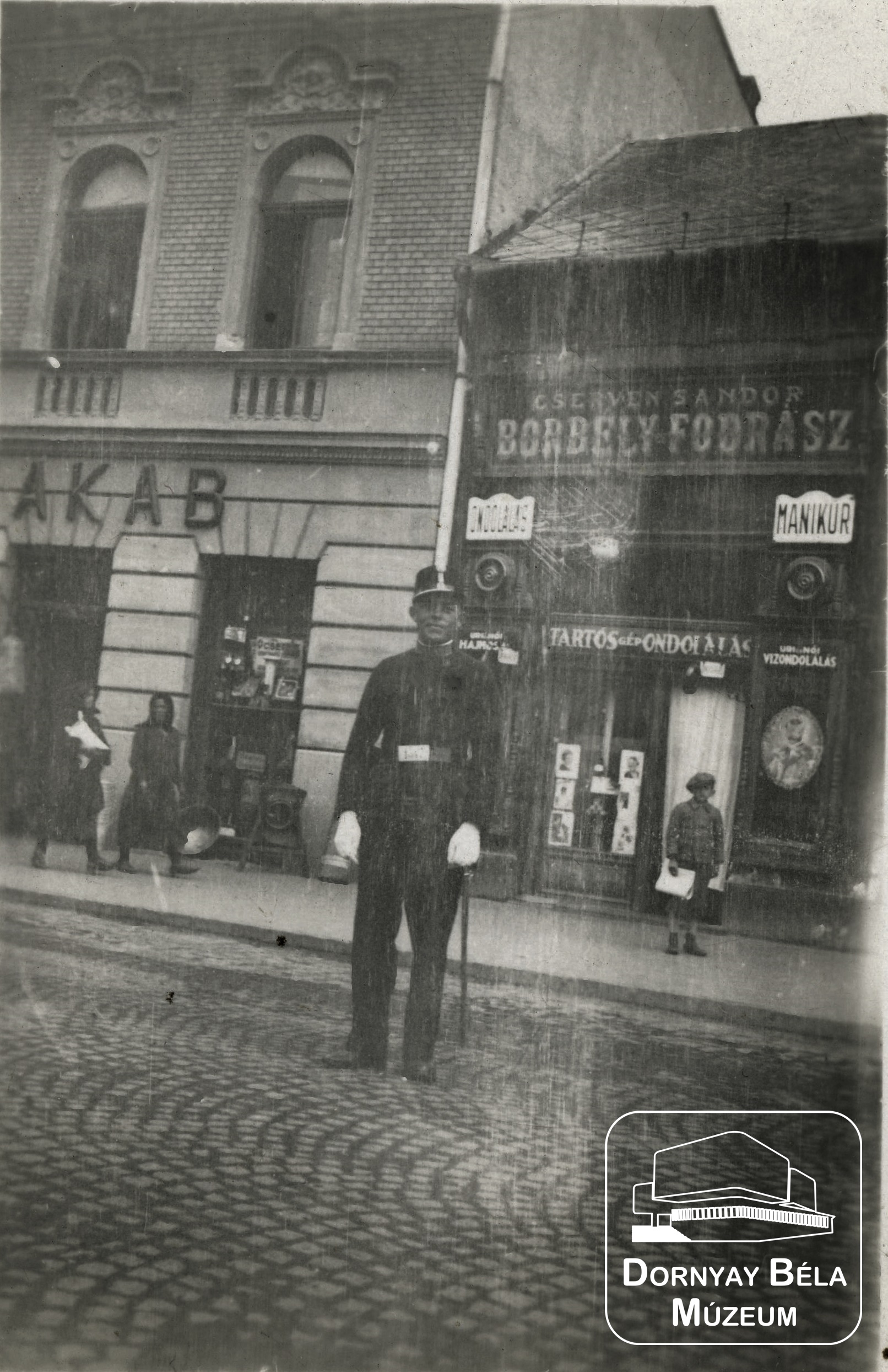 Cserven Sándor Borbély és Fodrász üzlete előtt álló katona. (Dornyay Béla Múzeum, Salgótarján CC BY-NC-SA)