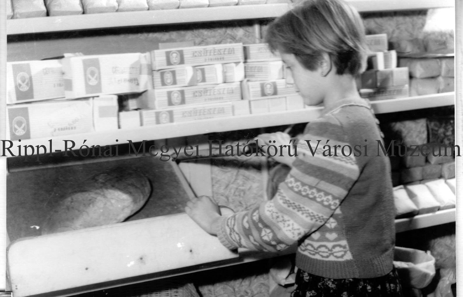 Az önkiszolgáló boltban az adagoló kar megnyomásával a pultra hullik a kenyér. (Rippl-Rónai Múzeum CC BY-NC-SA)