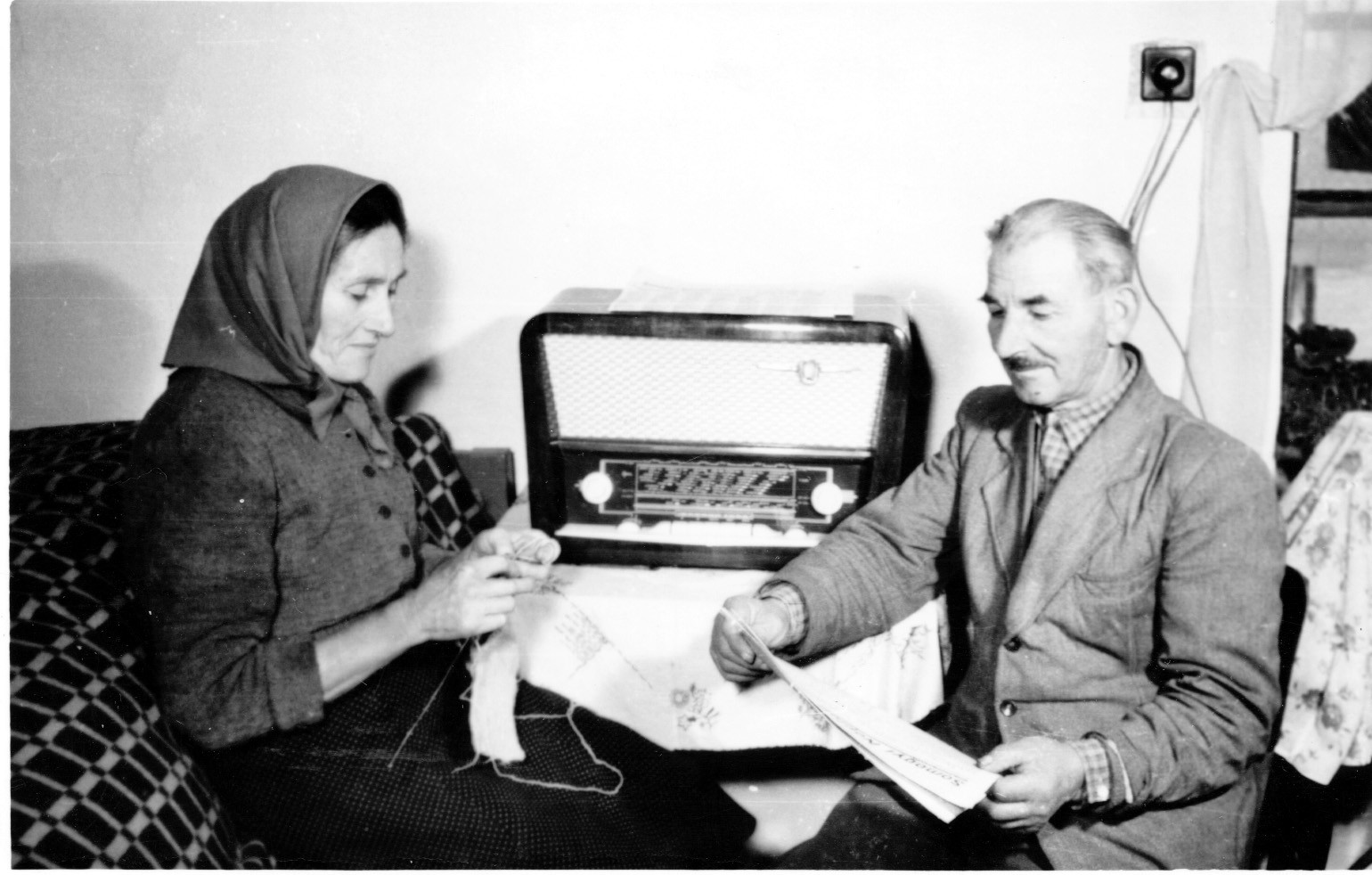 Horváth József és felesége, libickoznai tsz-tagok az asztali rádió mellett ülve. A nő kézimunkázik, a férfi Somogyi Néplapot olvas. (Rippl-Rónai Múzeum CC BY-NC-SA)