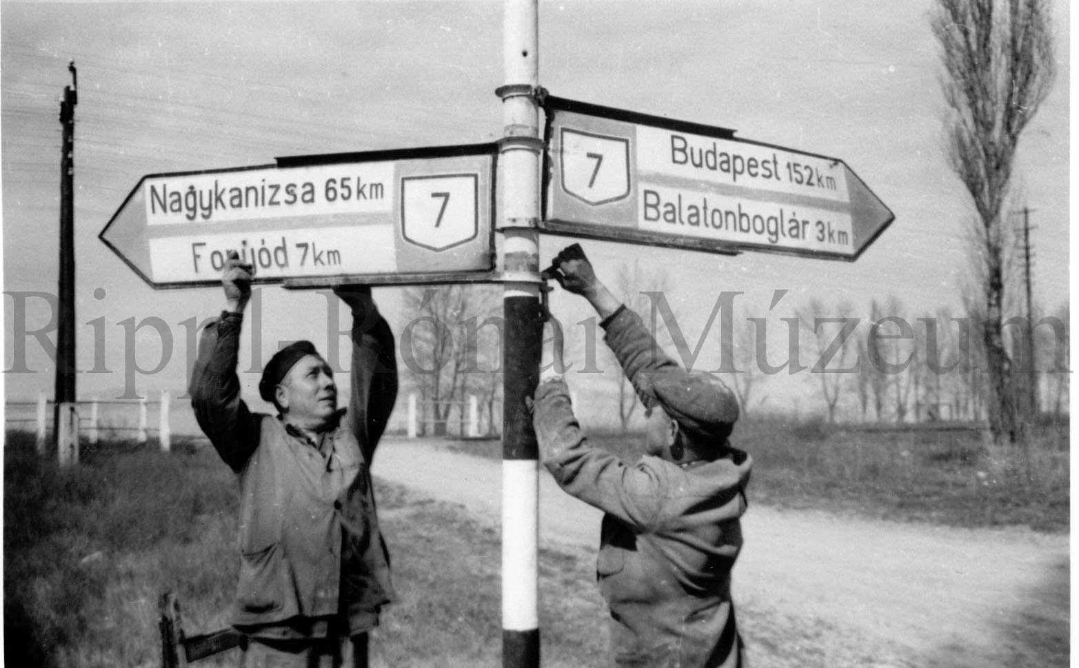 A 7-es országos főútvonalon útjelző táblát cserél Somogyi Lajos és Somogyvári Géza (Rippl-Rónai Múzeum CC BY-NC-SA)