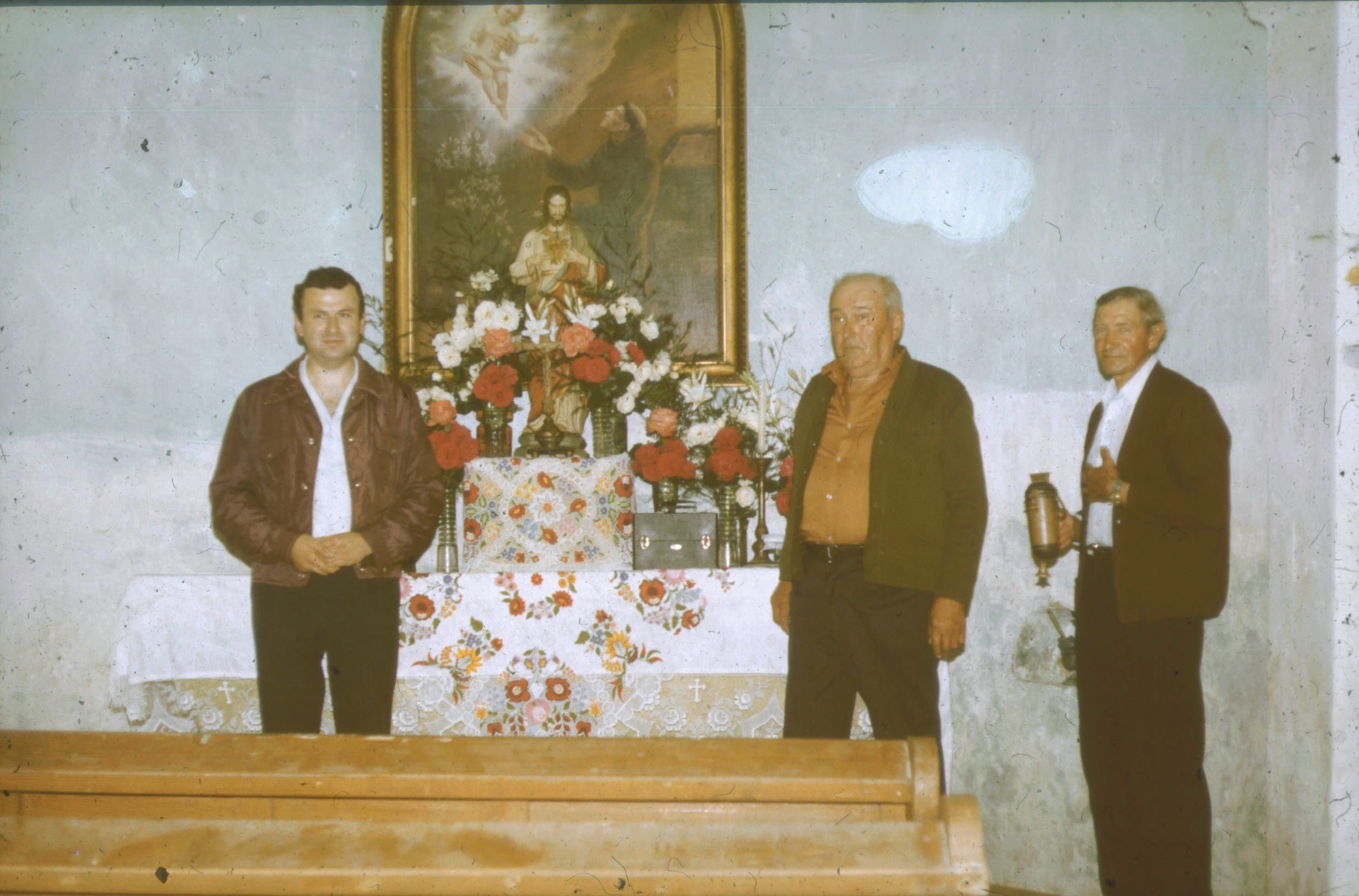 A plébánia papja és két egyházközségi képviselő a feldíszített oltár előtt (Rippl-Rónai Múzeum CC BY-NC-ND)