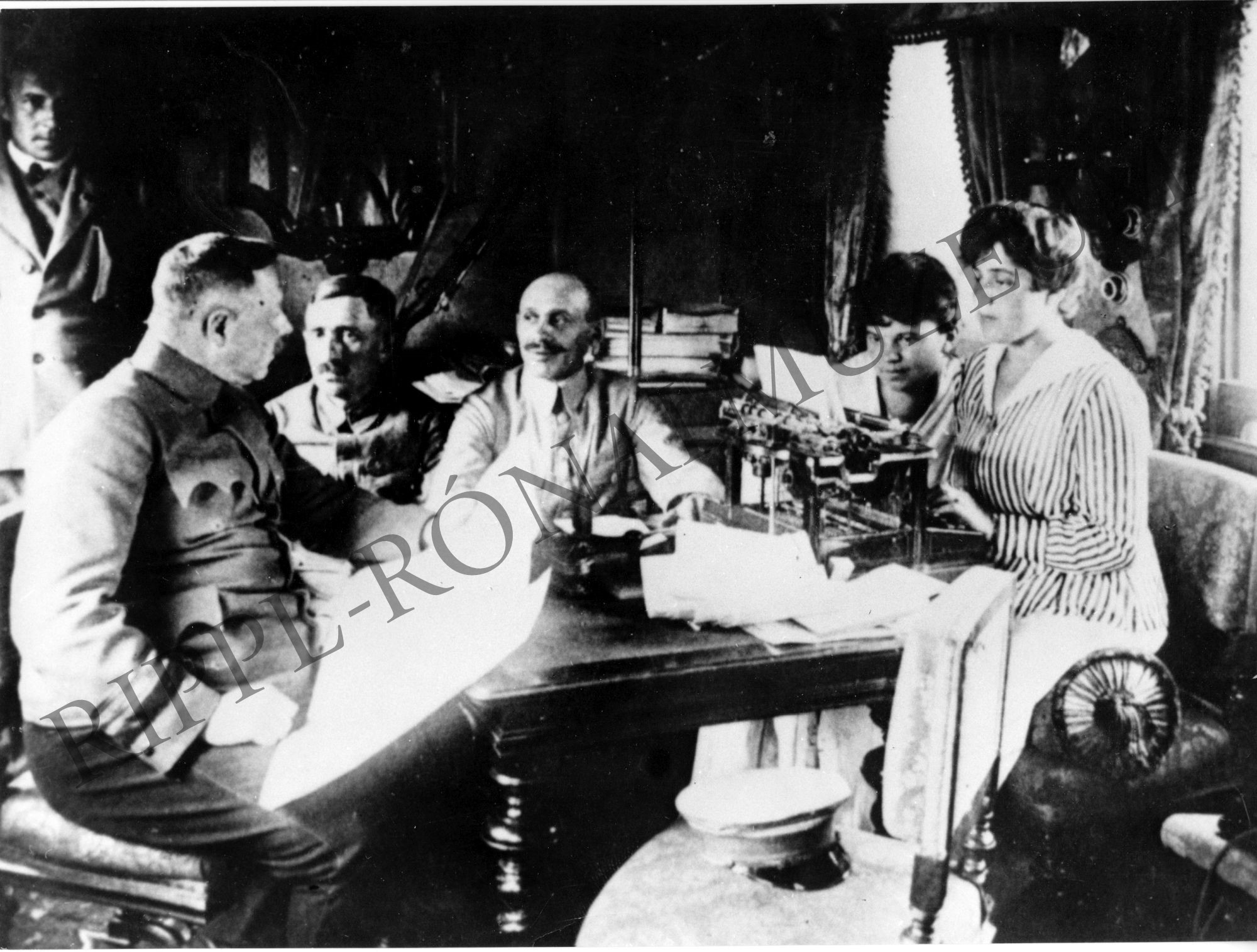 Stromfeld, Haubrich és Böhm tanácskozik. Egy csíkos kabátban, hosszú szoknyában lévő titkárnő írógéppel jegyzetel (Rippl-Rónai Múzeum CC BY-NC-SA)