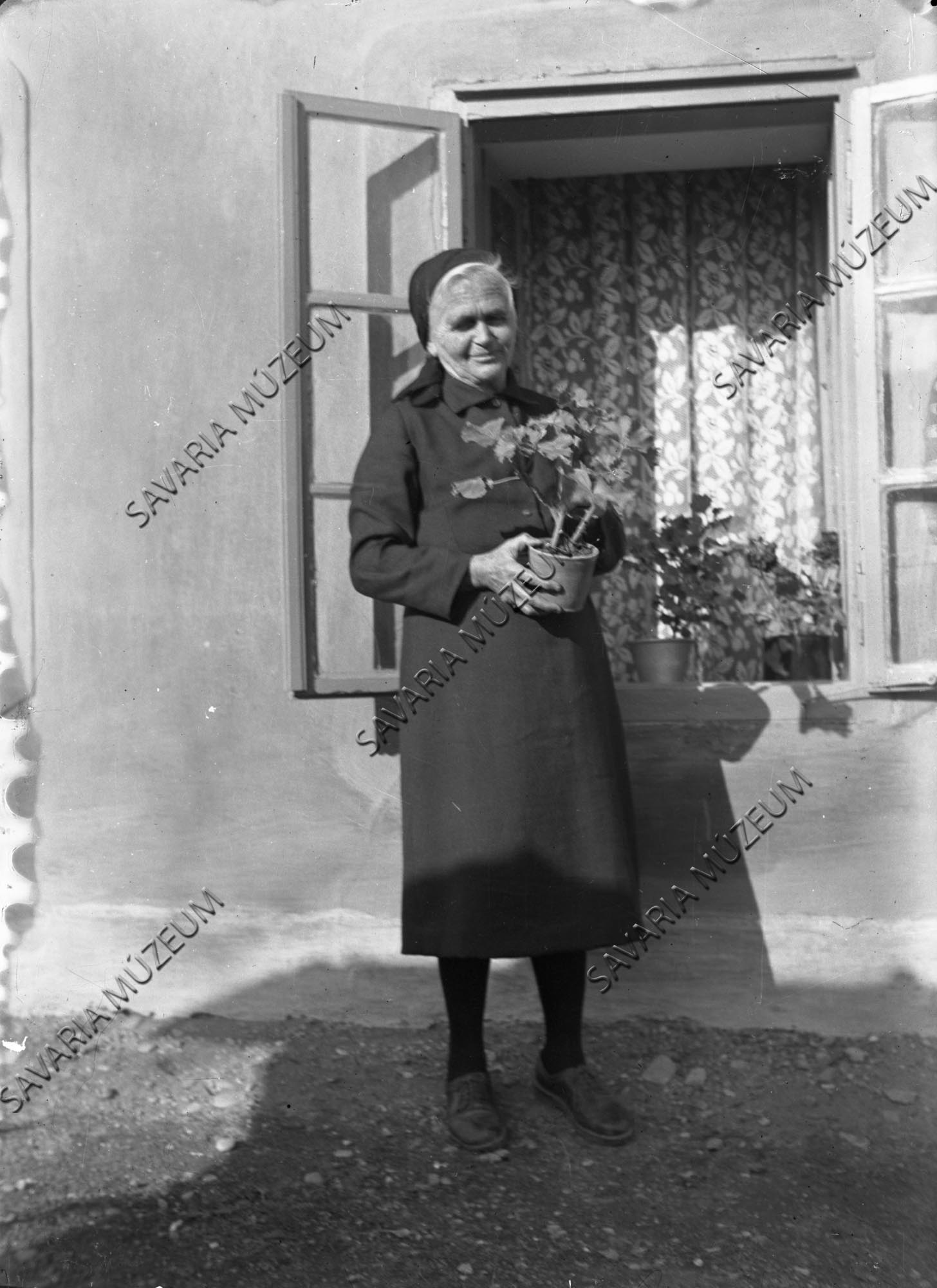 Asszony virággal az ablak előtt (Savaria Megyei Hatókörű Városi Múzeum, Szombathely CC BY-NC-SA)