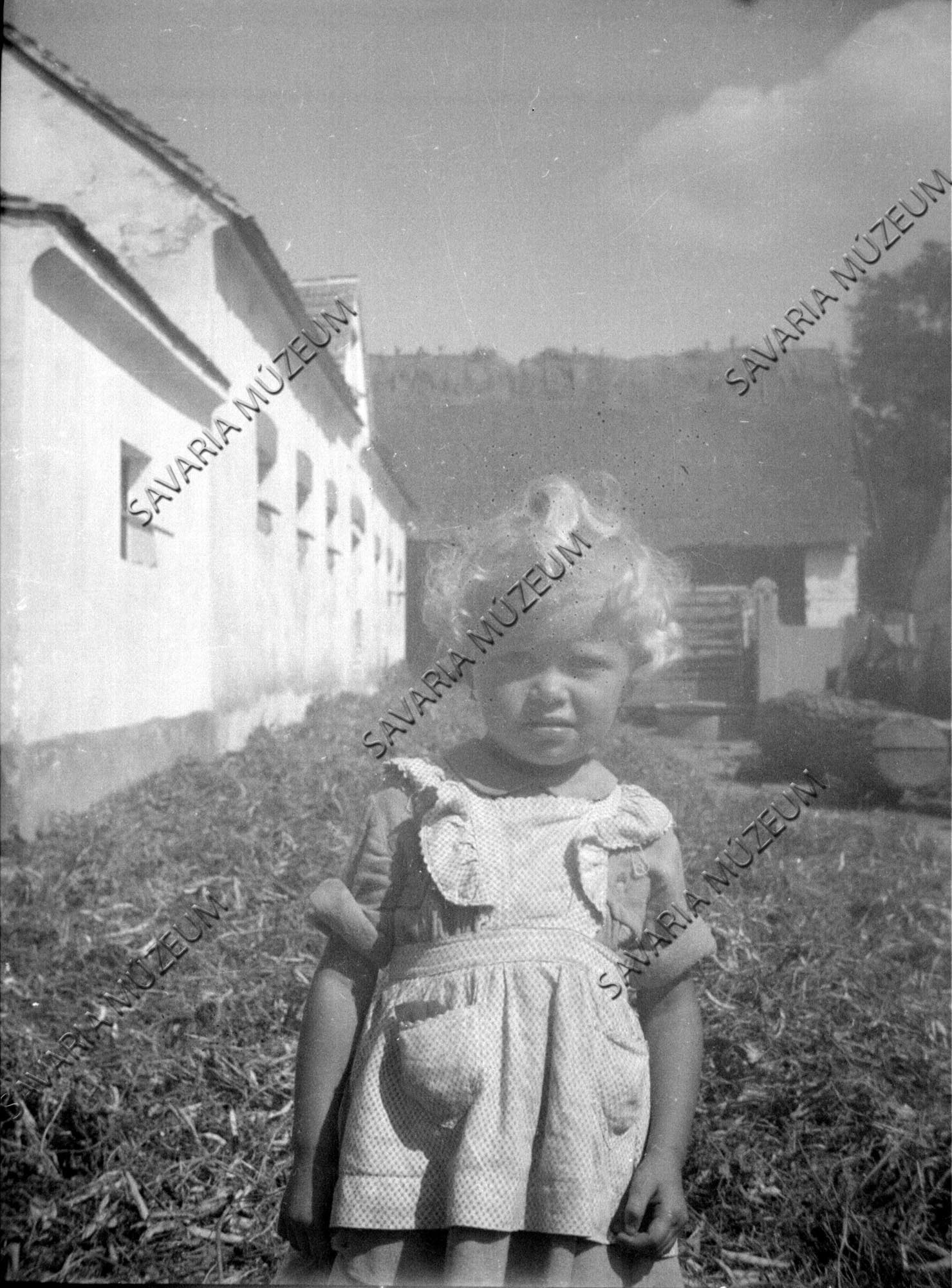 Kislány a tszcs-udvaron (Savaria Megyei Hatókörű Városi Múzeum, Szombathely CC BY-NC-SA)