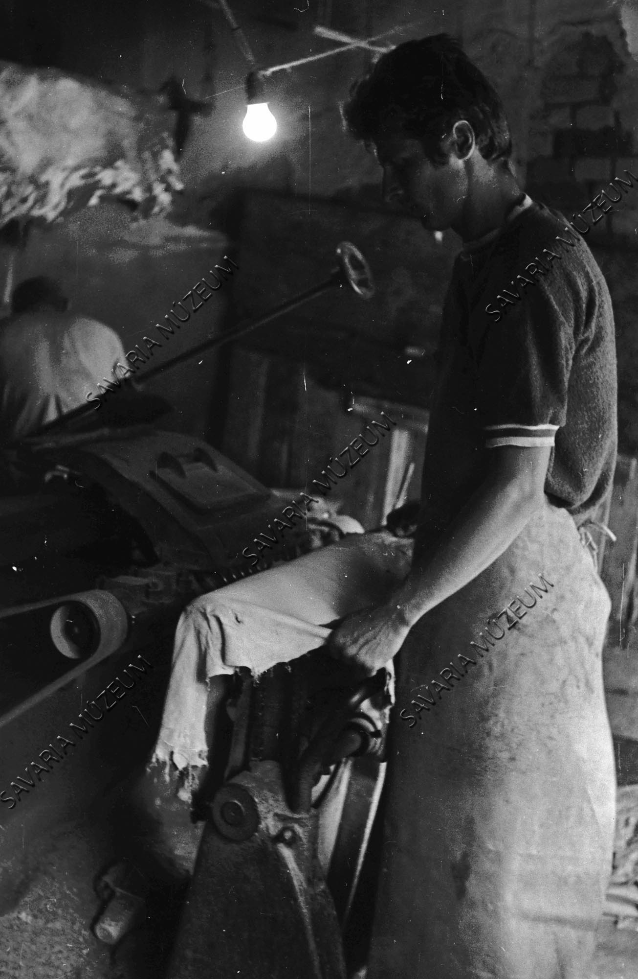 Tímár a kikészített bőrt gépen vékonyítja (Savaria Megyei Hatókörű Városi Múzeum, Szombathely CC BY-NC-SA)