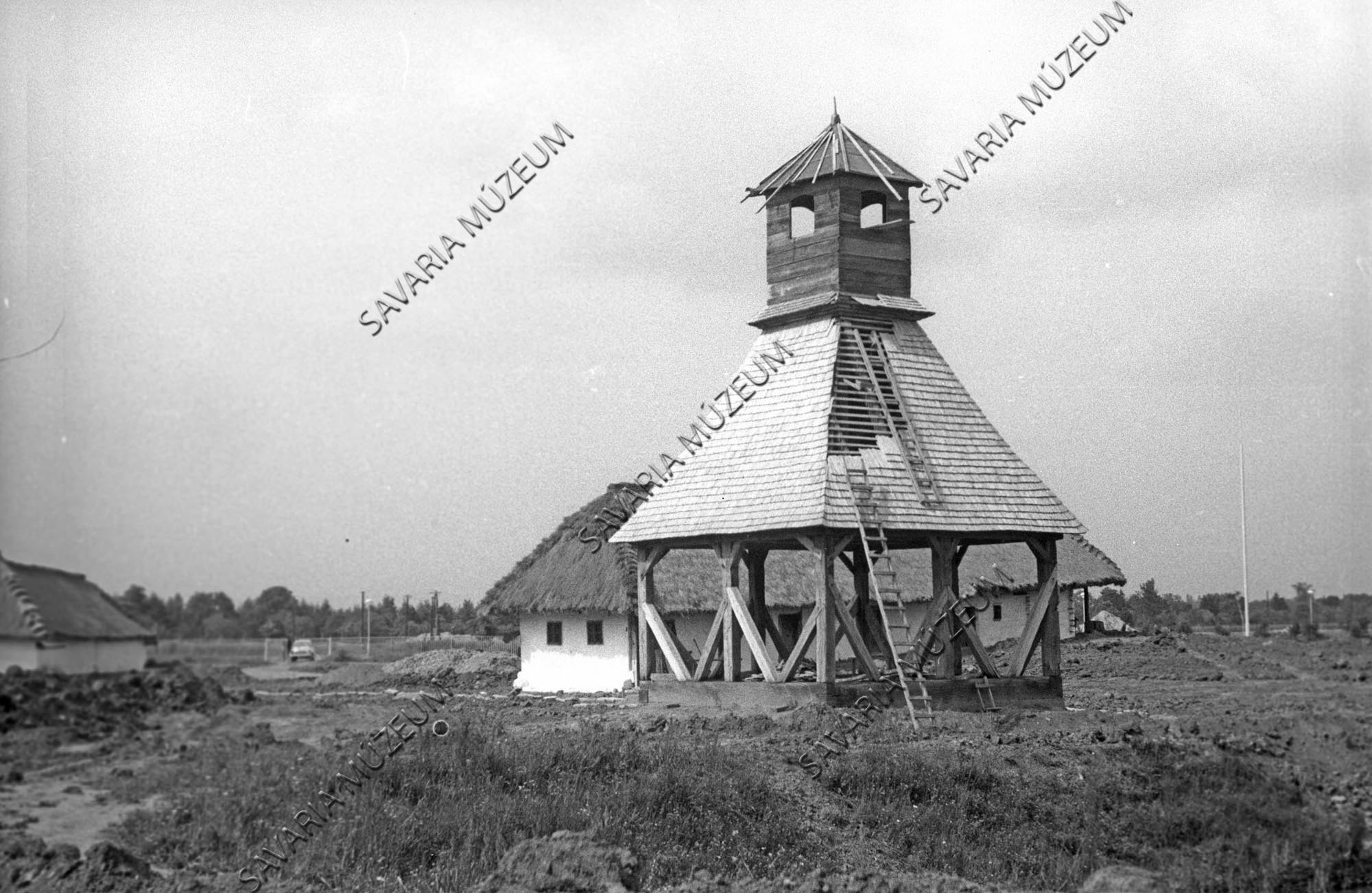Épülő molnaszecsődi harangláb és a szentpéterfai ház (Savaria Megyei Hatókörű Városi Múzeum, Szombathely CC BY-NC-SA)