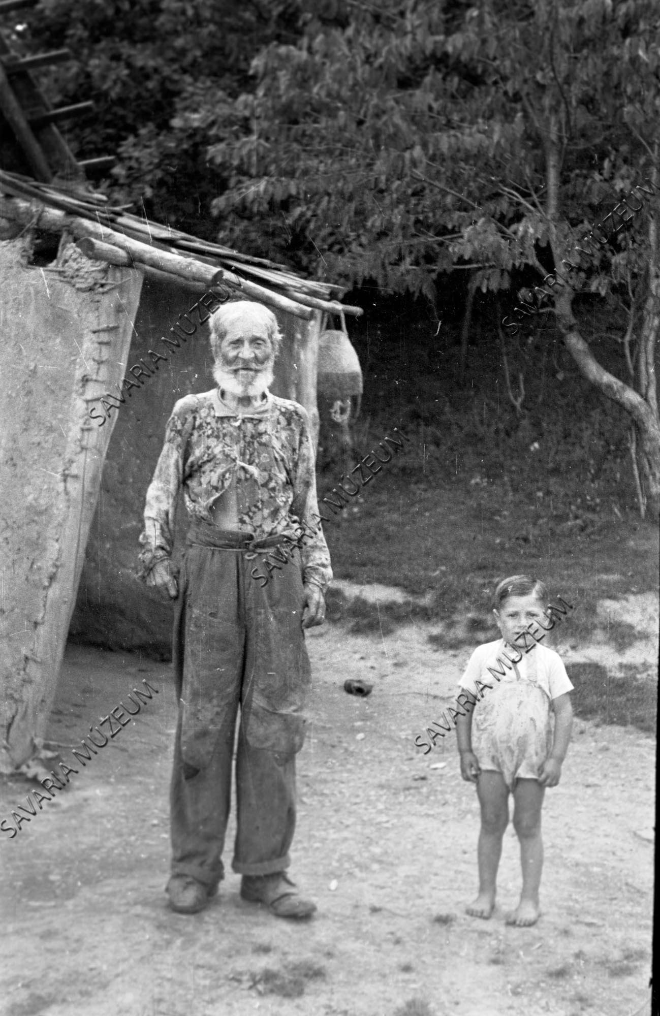 Öreg cigány kisfiúval a putri előtt (Savaria Megyei Hatókörű Városi Múzeum, Szombathely CC BY-NC-SA)