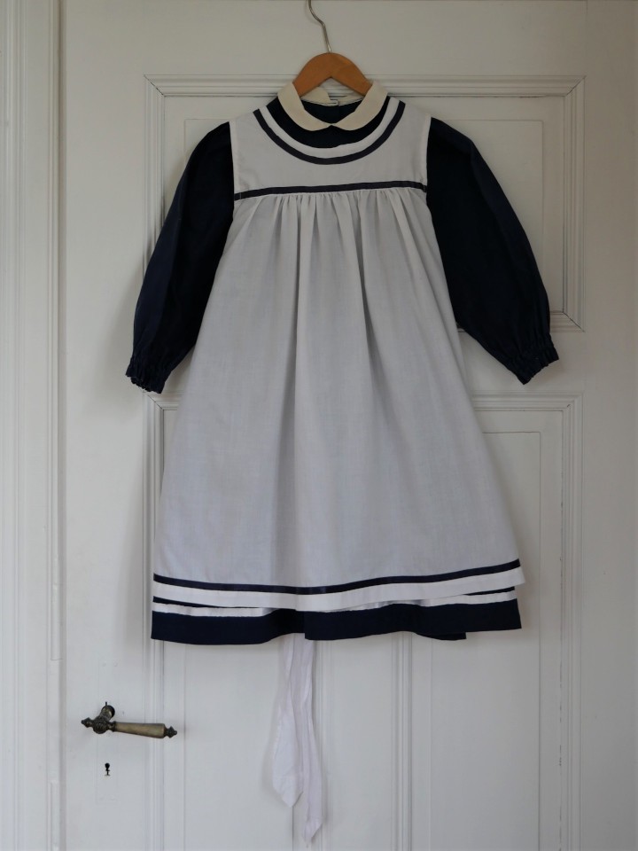 Dunkelblaues Mädchenkleid mit weißer Schürze (Museumsschule Hiddenhausen CC BY-NC-SA)