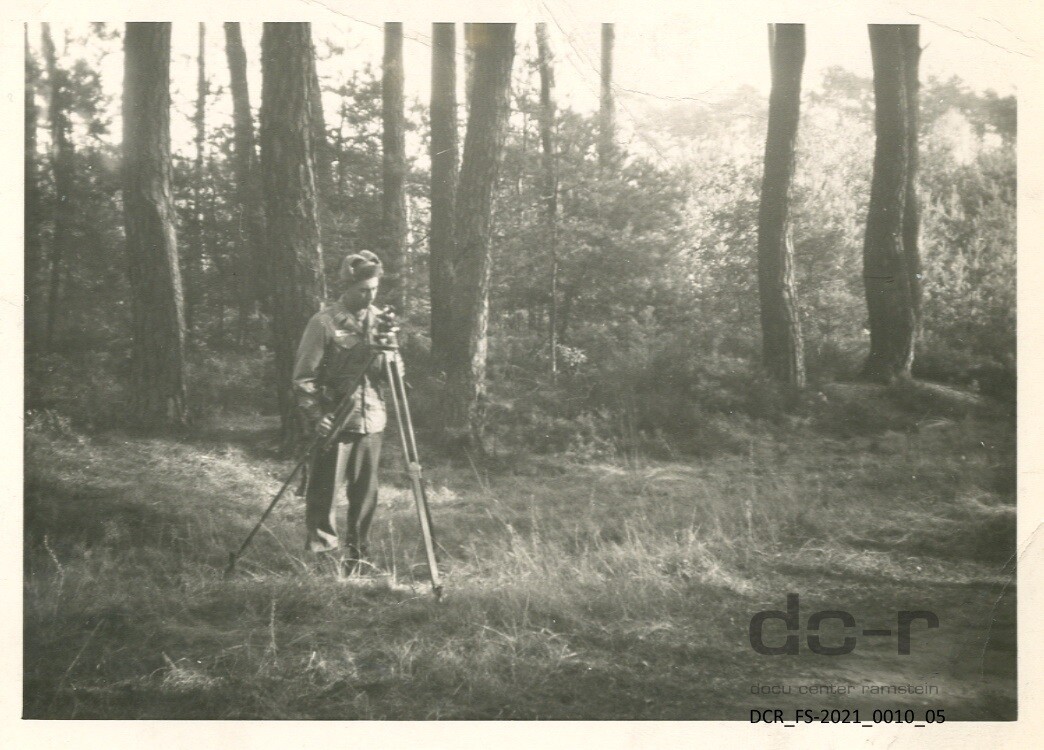 Schwarzweißfoto, eines Fotografen mit Kamera und Stativ ("dc-r" docu center ramstein RR-F)