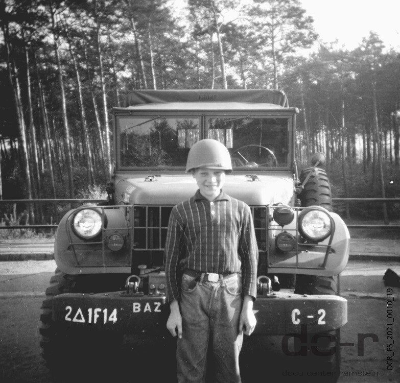 Schwarzweißfoto eines 11-jährigen Jungen vor einem Militärfahrzeug ("dc-r" docu center ramstein RR-F)